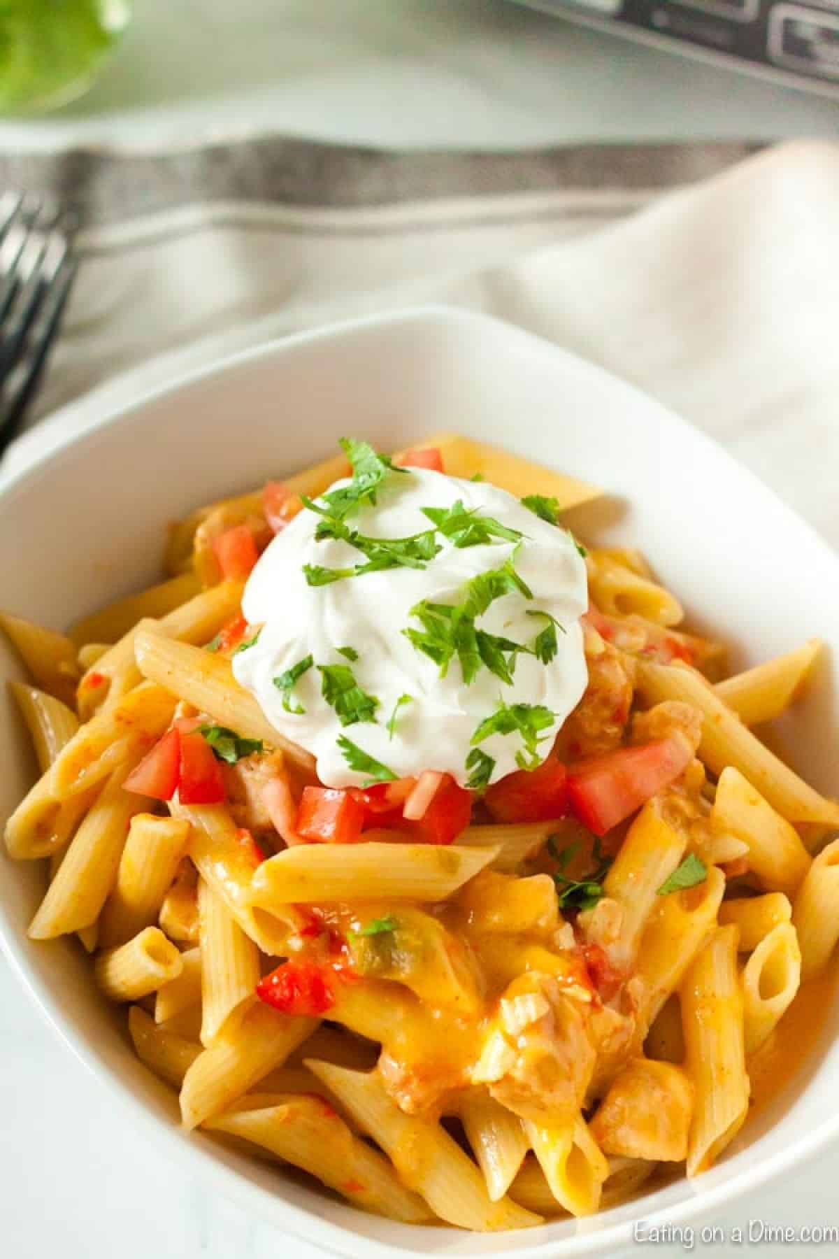 Chicken Fajita Pasta in a bowl topped with sour cream and diced tomatoes
