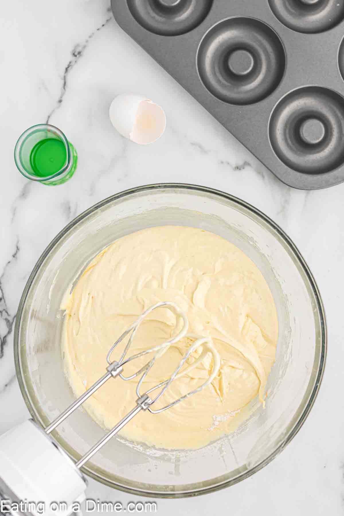 Combining the cake mix donut batter in a bowl with a electric mixer