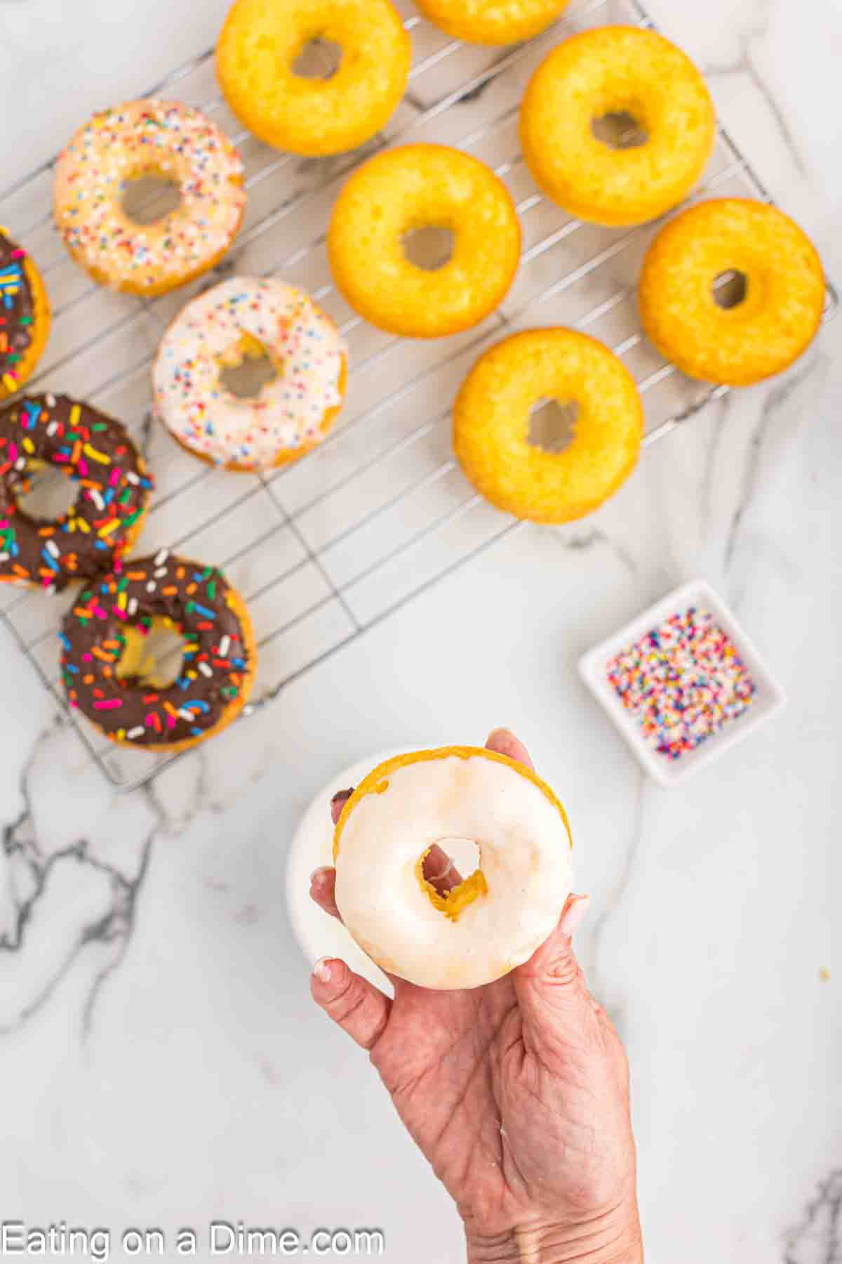 Donuts dipped into vanilla glaze and chocolate glaze with sprinkles cooling on a cooling rack