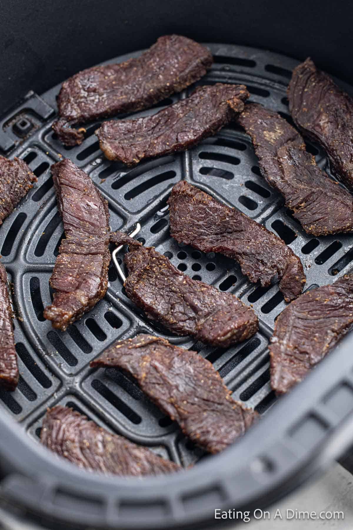 Beef jerky strips in an air fryer baskey