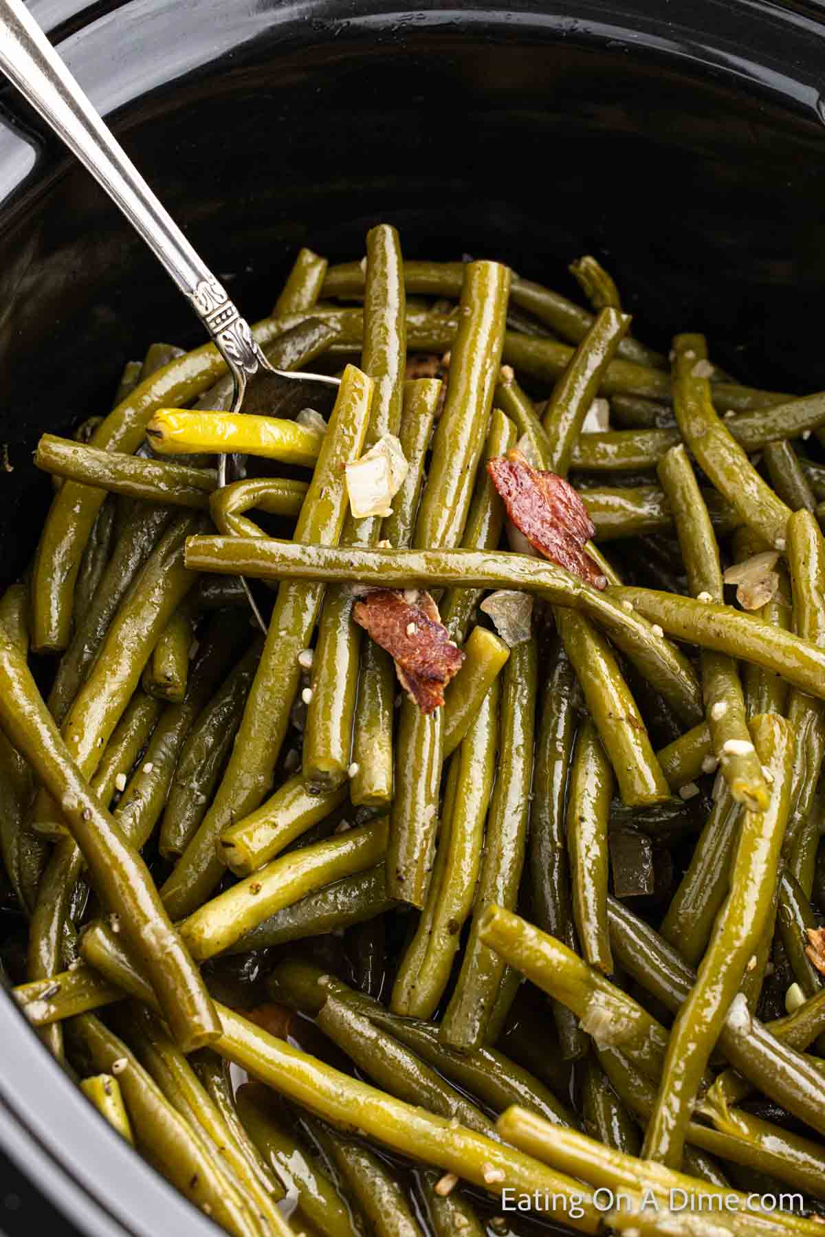 Cooked Fresh Green Beans in the slow cooker topped with chopped bacon and onions