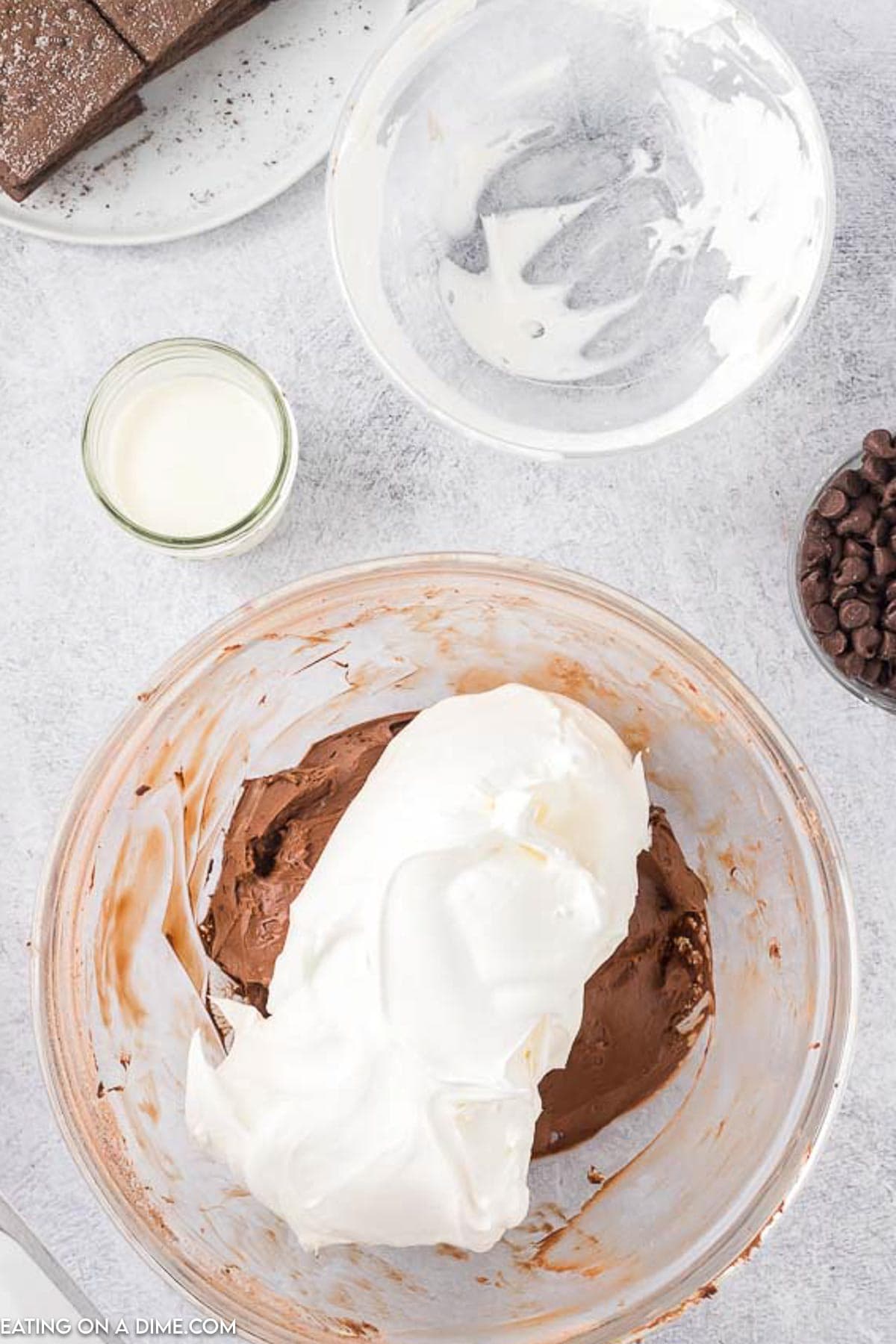 Topping the chocolate mixture with cool whip in a bowl