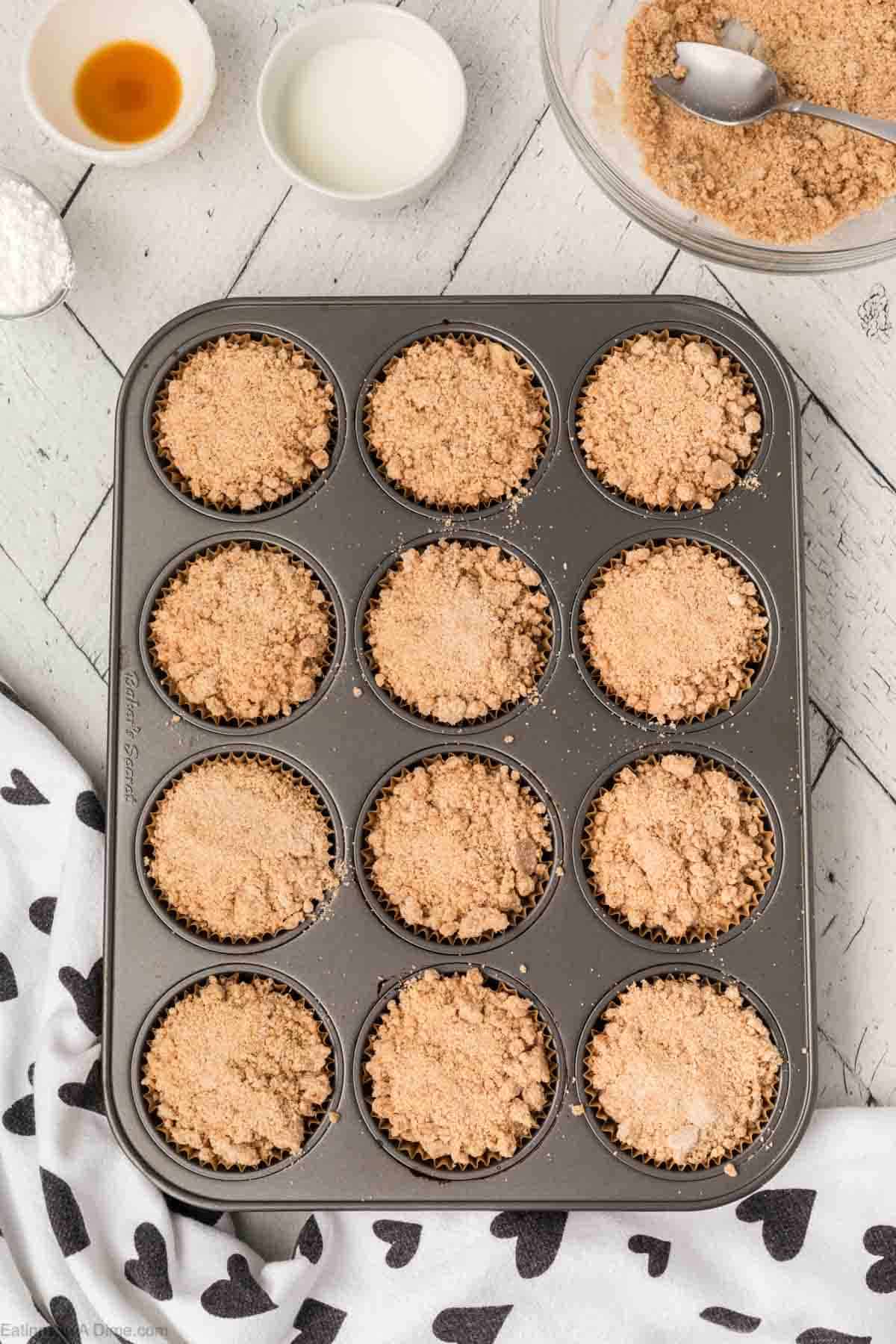 Topping the crumble mixture to the muffin batter in the muffin pan