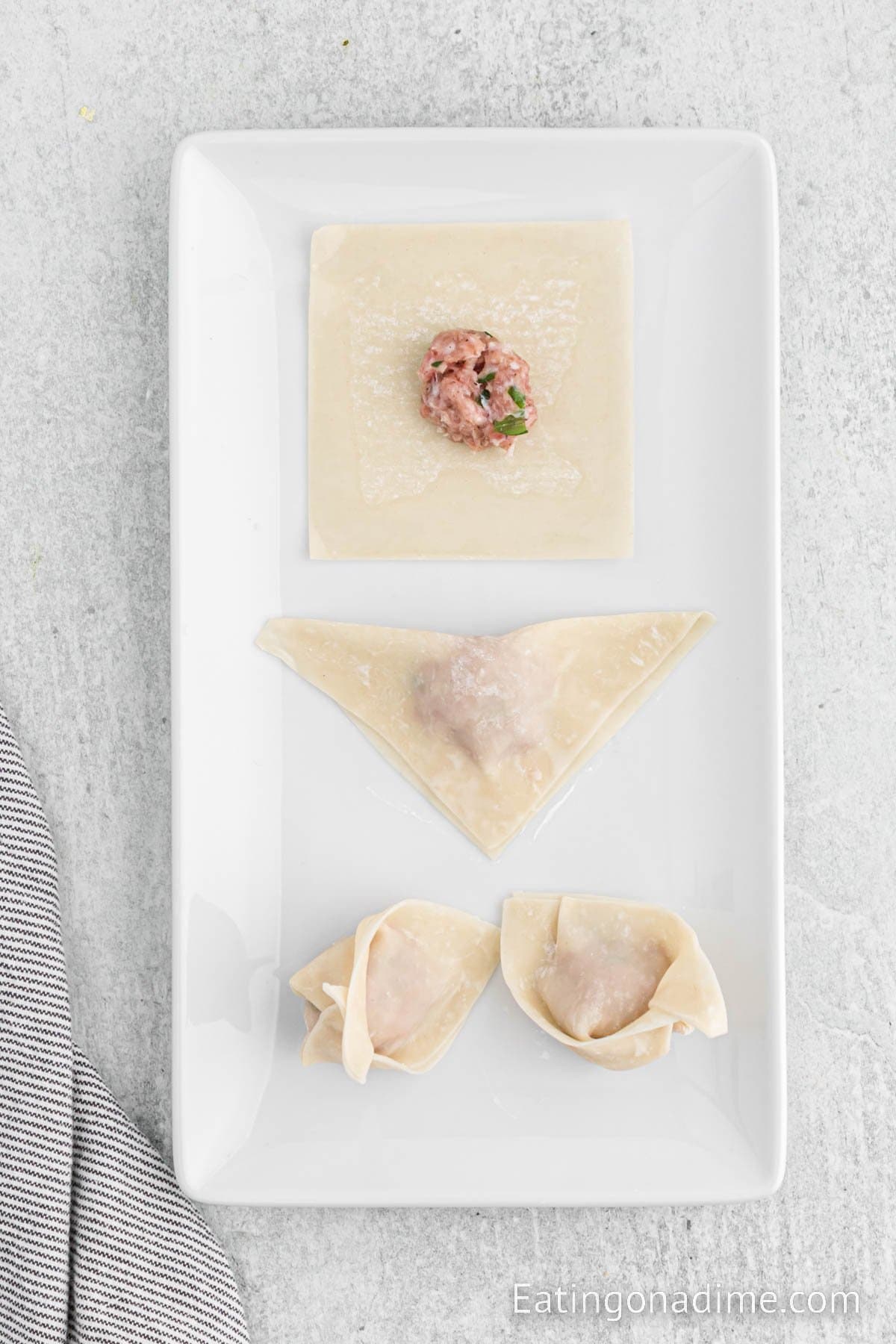 Filling the wonton papers with ground pork mixture with then sealing them