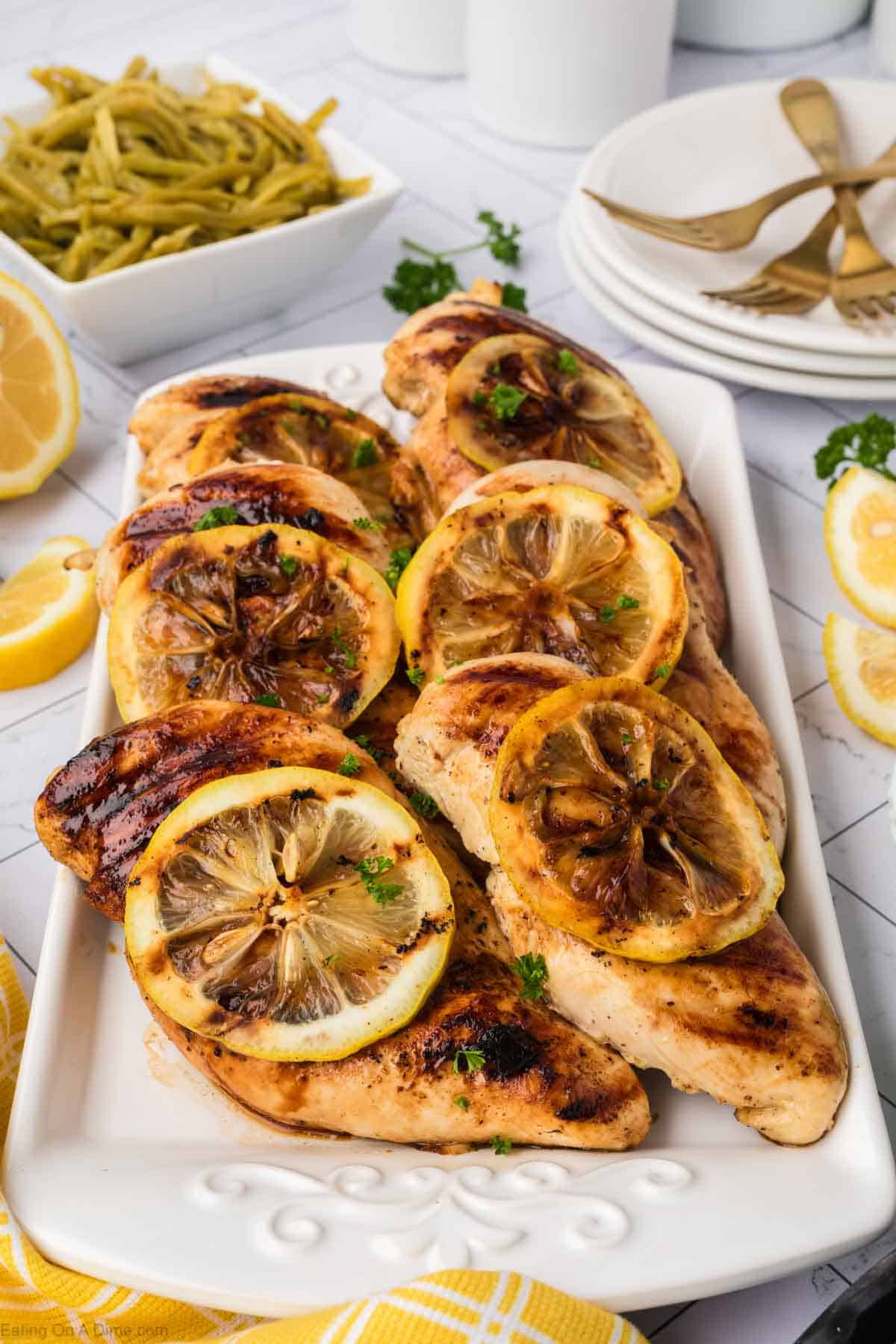 Chicken breast on a platter topped with slice lemons