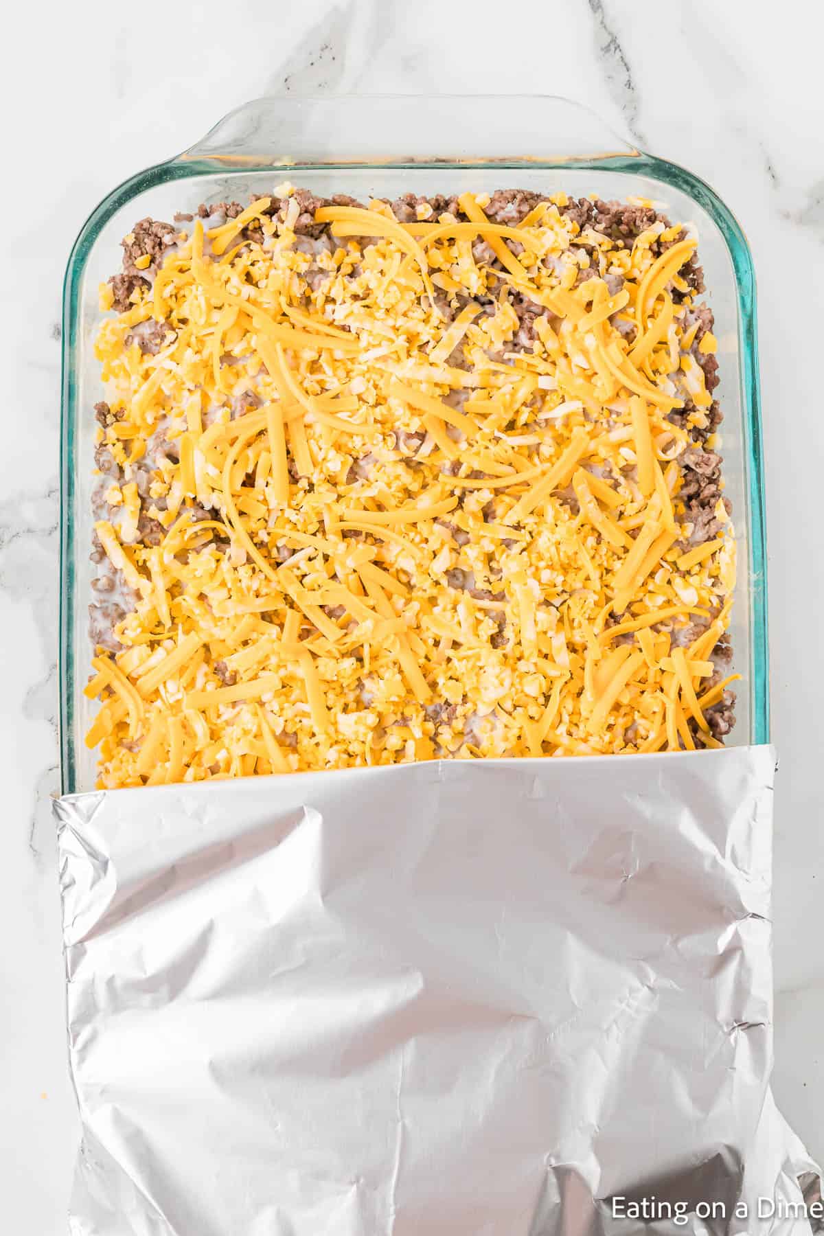 Covering the hamburger potato casserole with foil in a baking dish