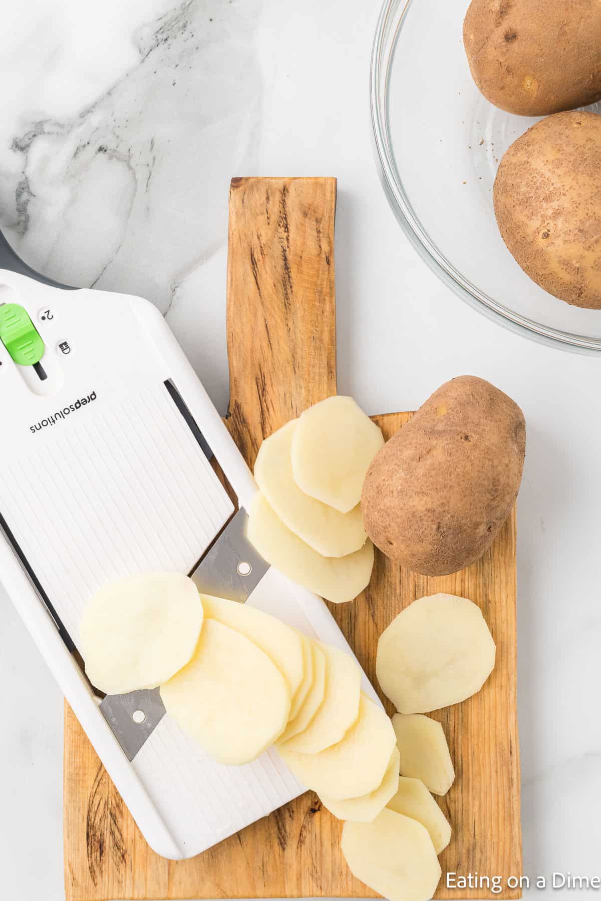 Sliced potatoes on a cutting board with a slicer