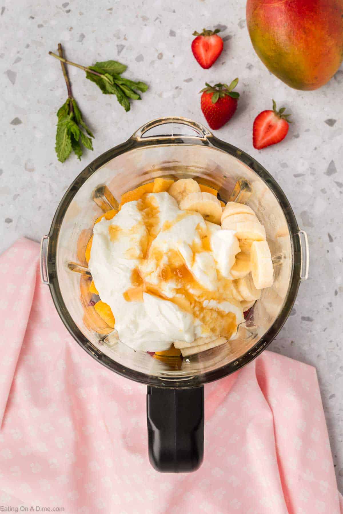 Adding the mango, bananas, yogurt and honey to the blender