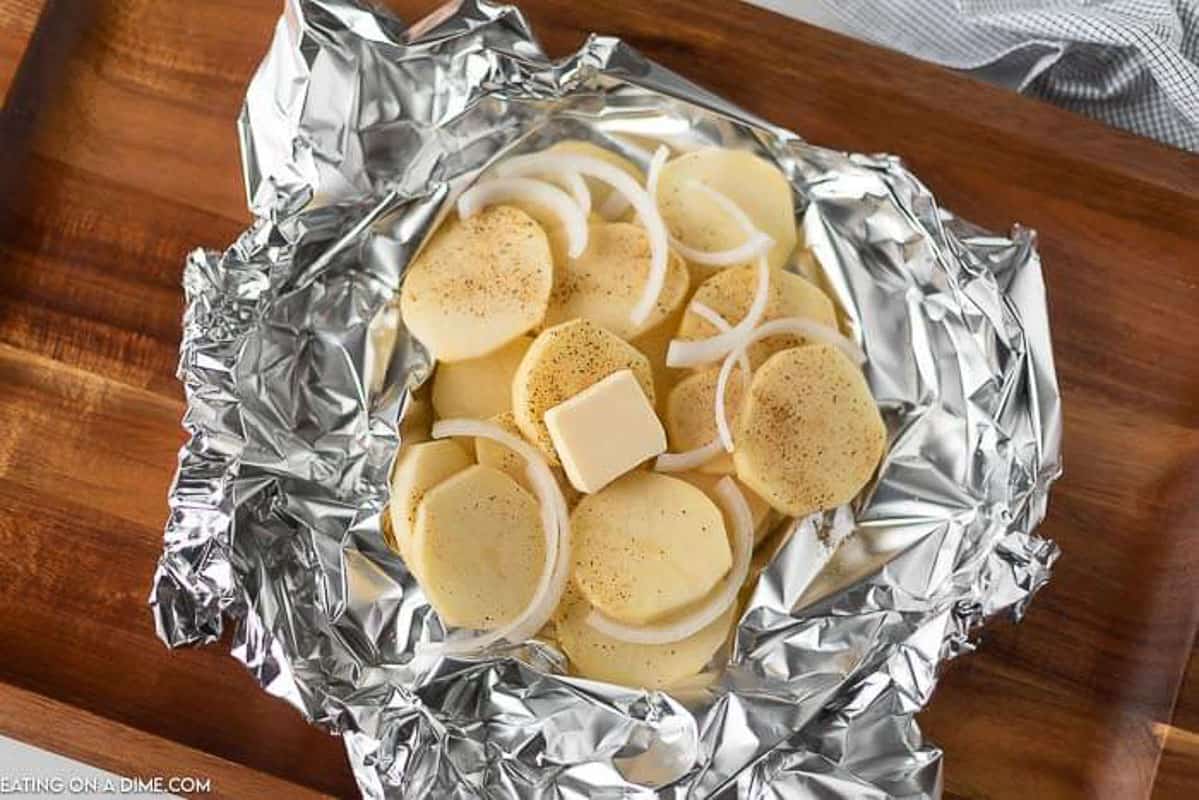 Slice potatoes in foil topped with onion, seasoning and butter