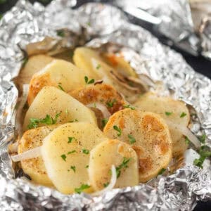 Slice foil potatoes cooked with onions on foil.