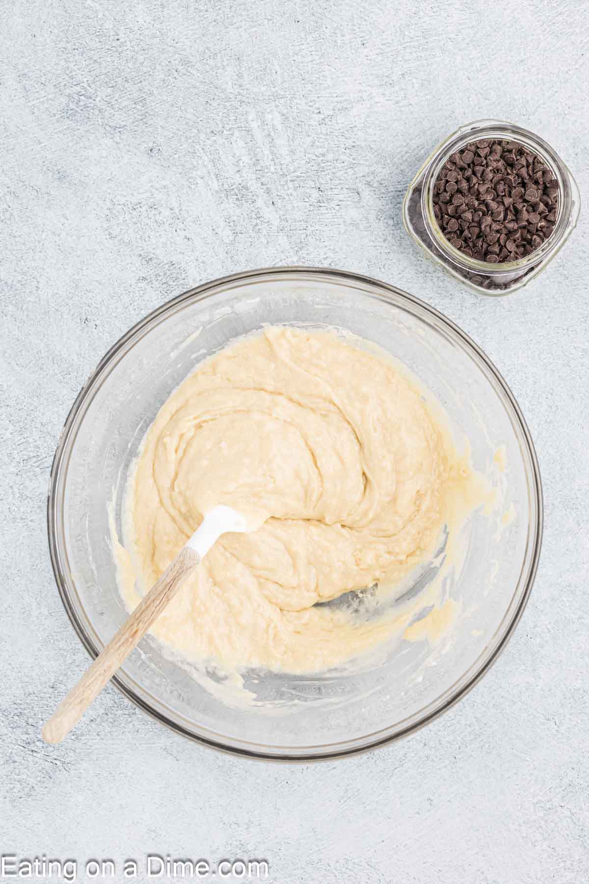Combining the muffin batter in a bowl with a jar of chocolate chips