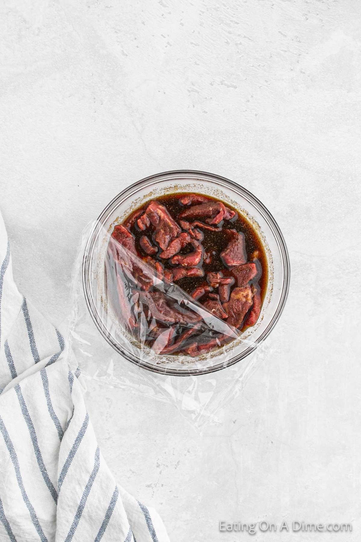 Marinating the beef strips in a bowl