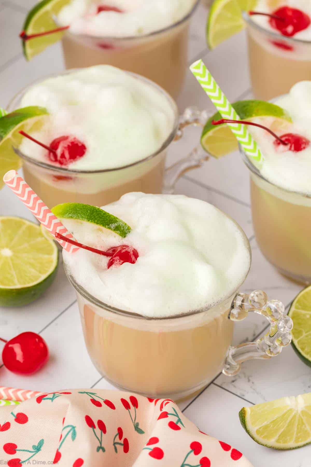 Cherry Limeade Sherbet Punch in clear glasses topped with a lime wedge and cherries