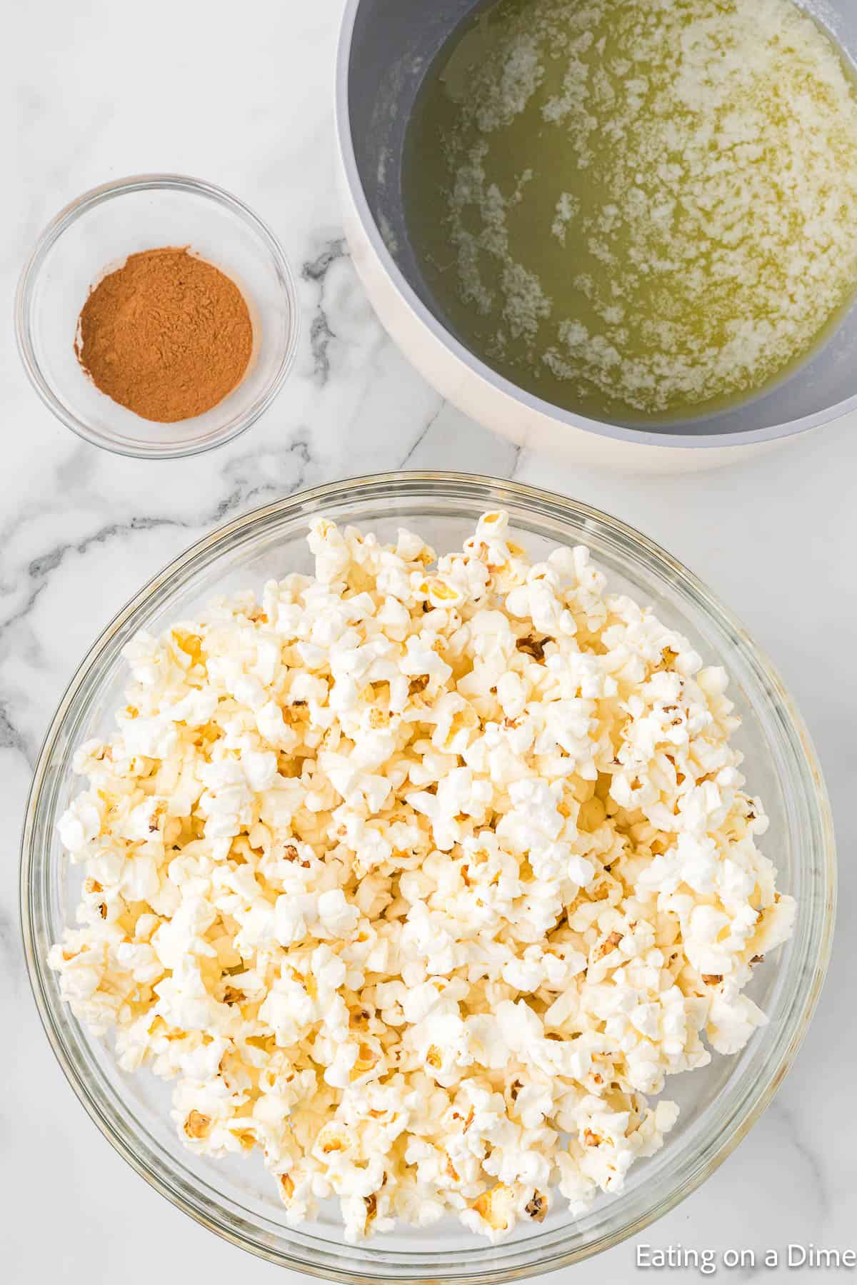 Popcorn in a bowl with a bowl of melted butter and cinnamon