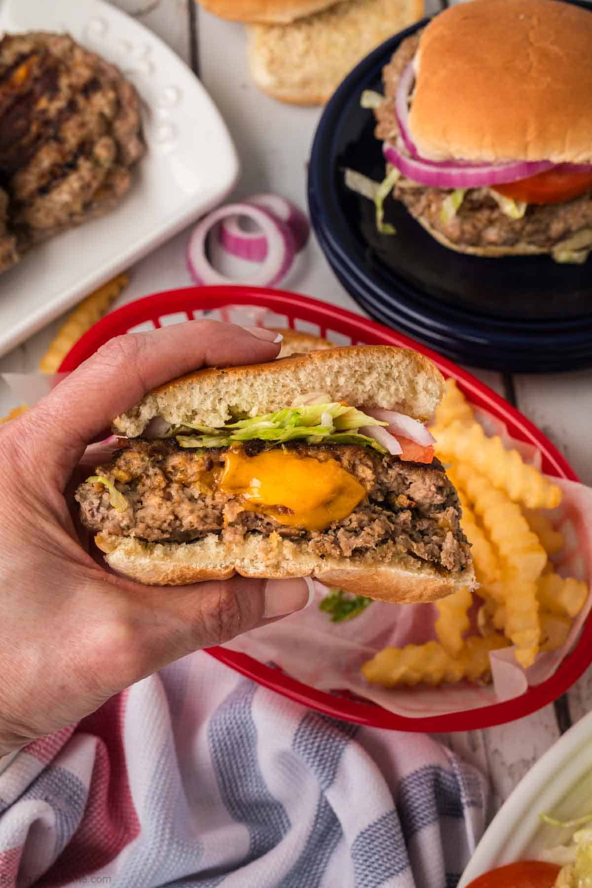 Half of Crack Burger being held with the center of the burger full of melted cheese
