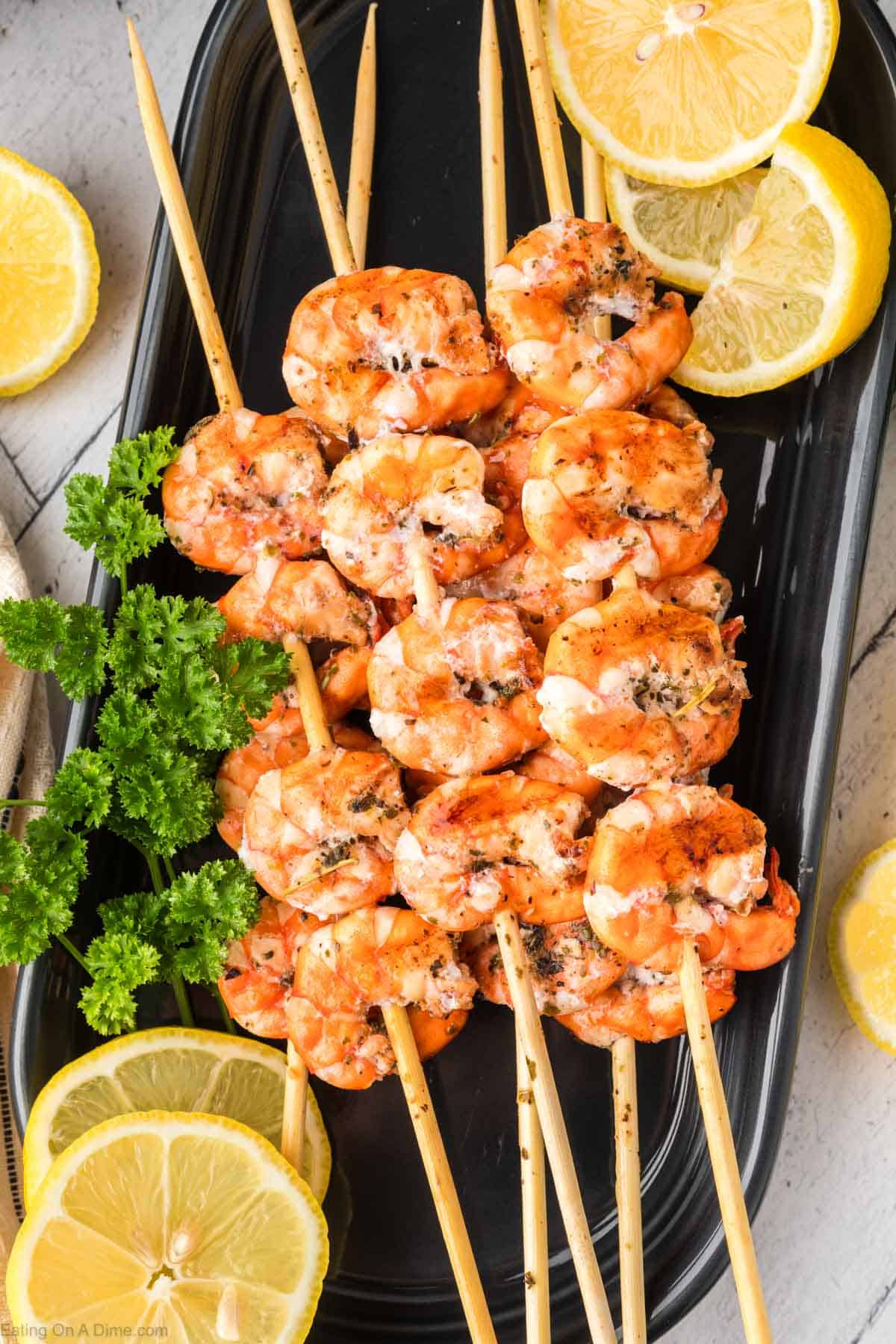 Grilled shrimp skewers on a plate with fresh lemon slices