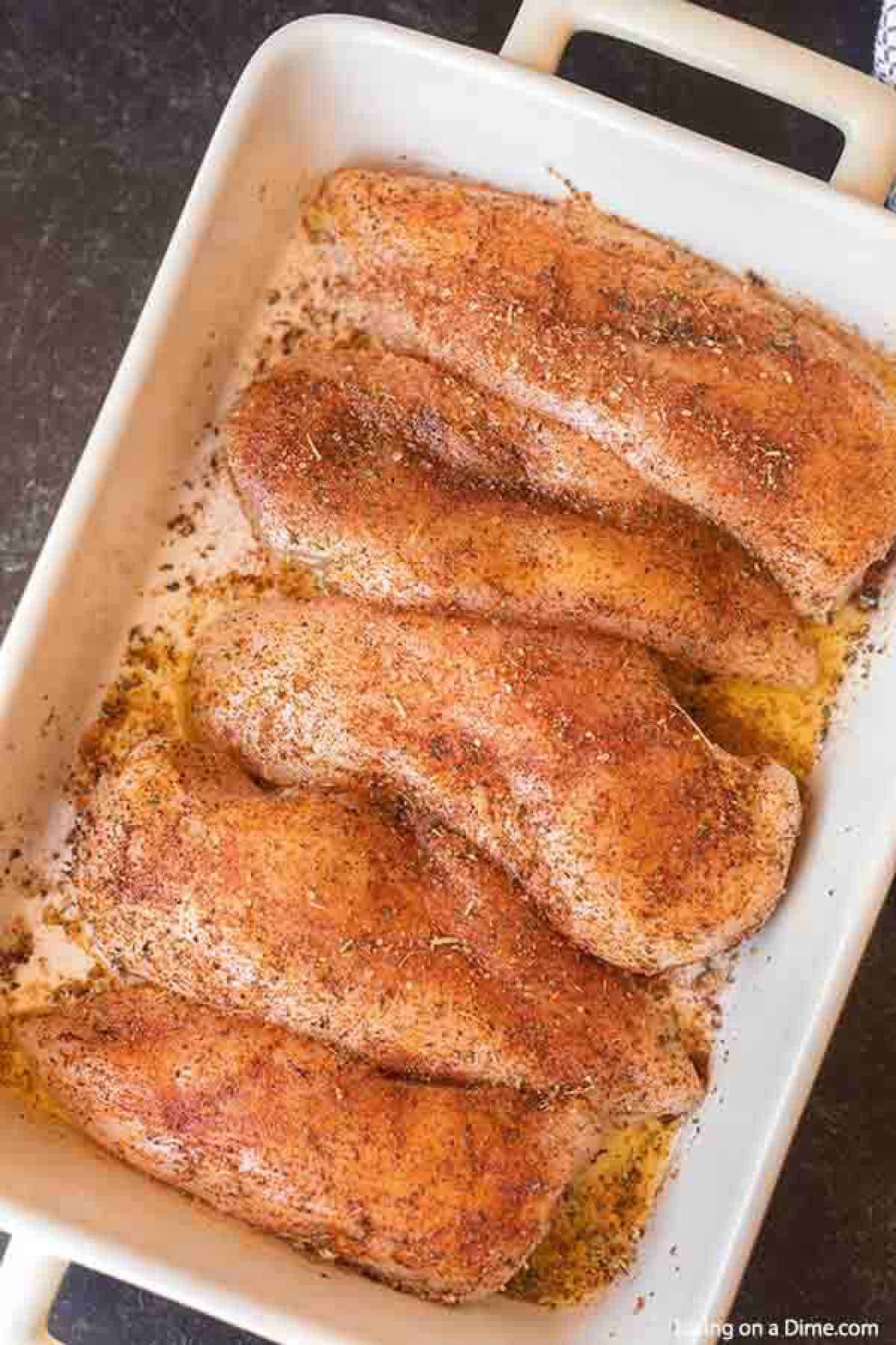 Seasoning chicken breast in a baking dish