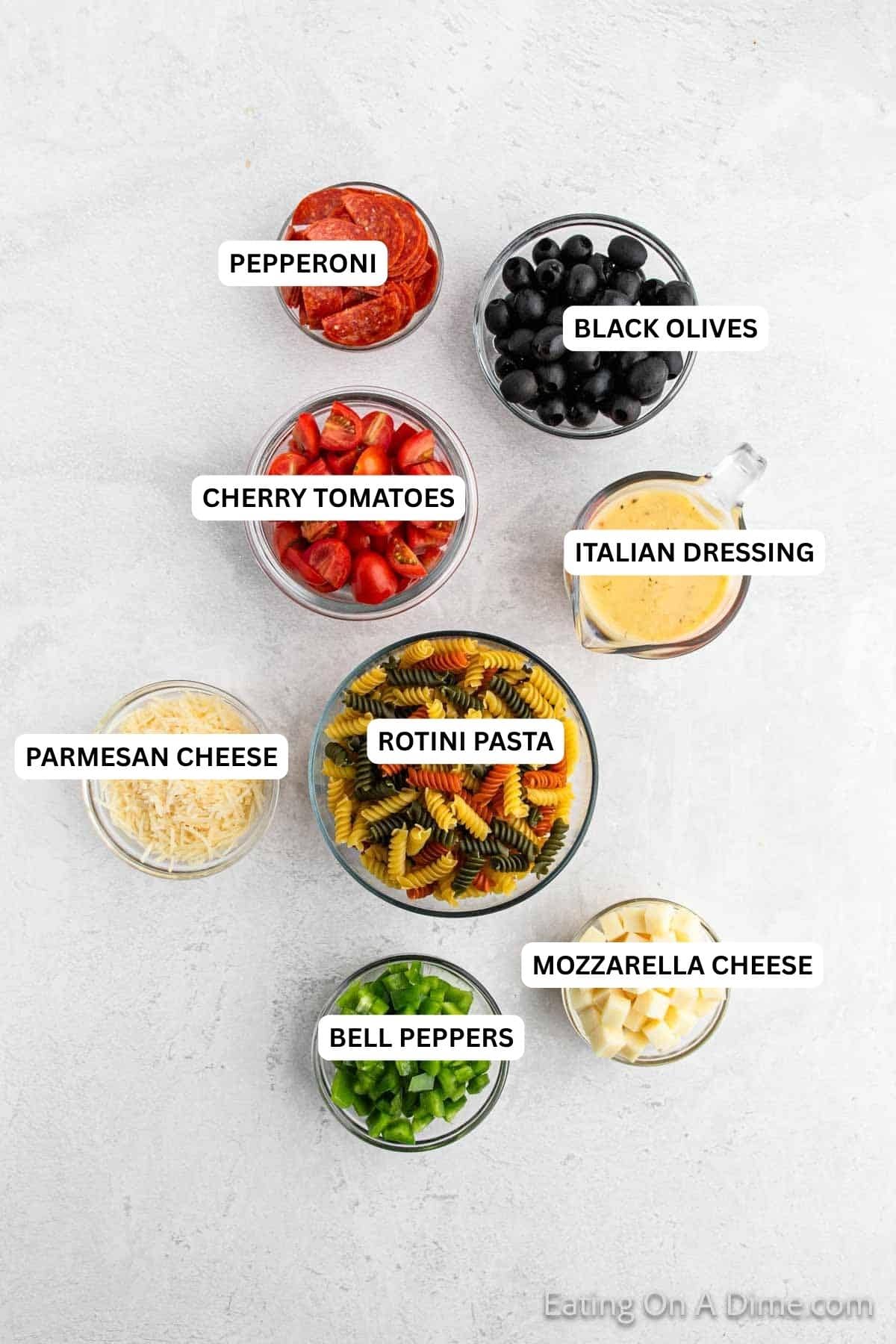 Ingredients for recipe: pepperoni, black olives, cherry tomatoes, Italian dressing, rotini pasta, Parmesan cheese, bell peppers and mozzarella cheese.