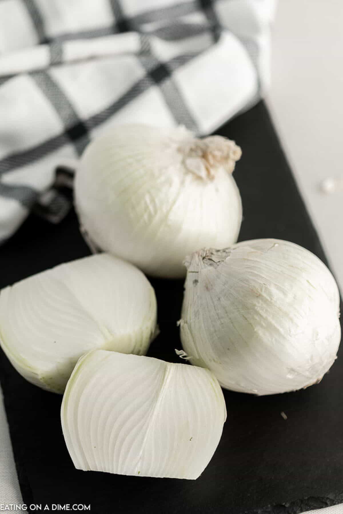 Close up image of whole onions on a cutting board.