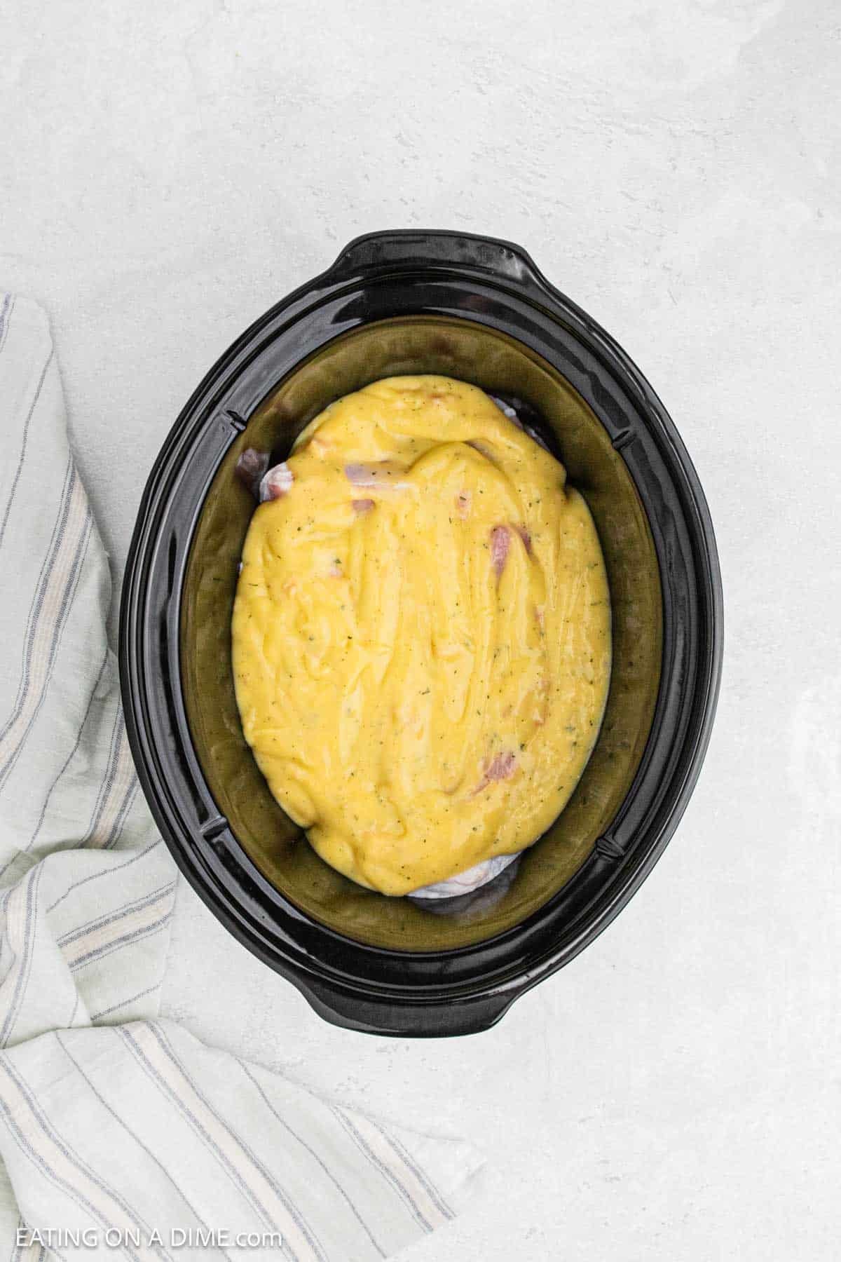 Cream of chicken soup mixture spread over the top of the pork chops in the crock pot.