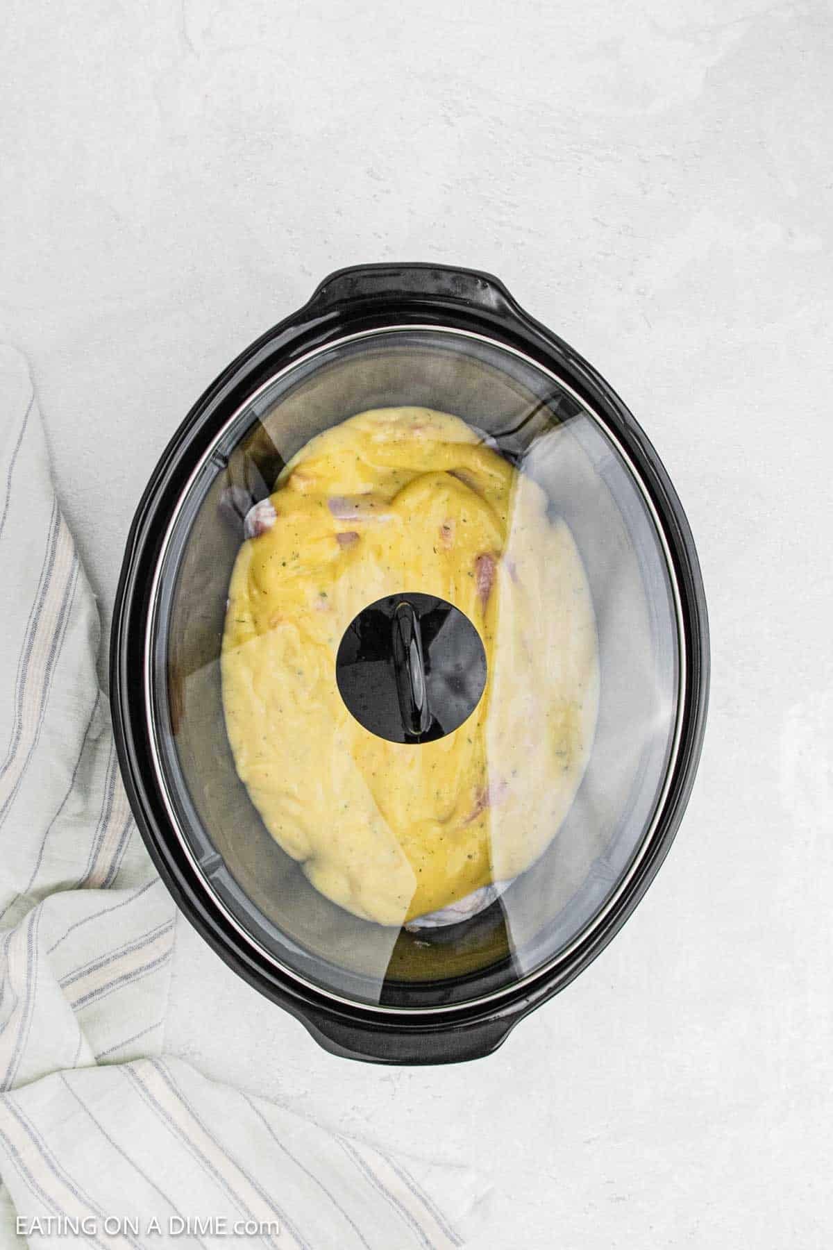 Lid placed on the crock pot with the pork chops covered with cream of chicken mixture.
