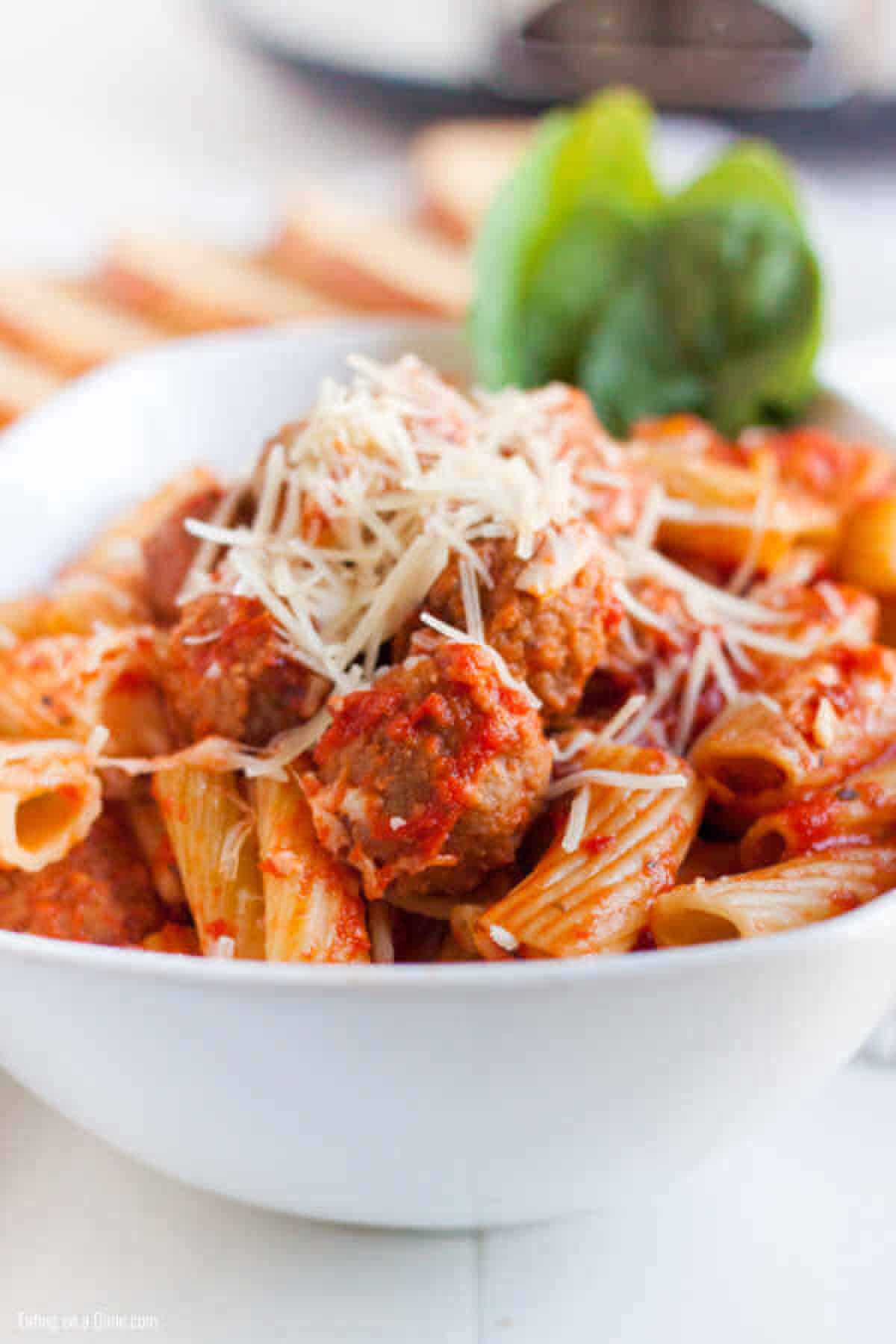 This Crock pot Baked Pasta with Meatballs recipe is tasty and takes minutes to toss in your crockpot. Slow cooker pasta bake with meatballs is so easy. bowl of pasta and meatballs
