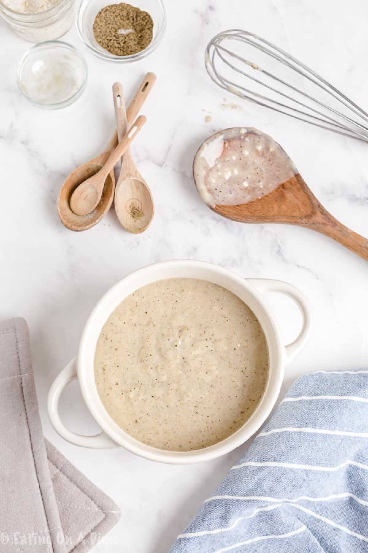 Try this easy homemade cream of chicken soup recipe next time you need a can for your favorite recipe. It is cheaper and much healthier to make at home. Cream of Chicken Soup in a white bowl with a wooden spoon on the side of wooden tablespoons