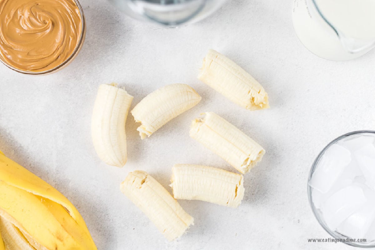 Banana cut into halves with a bowl of peanut butter on the side