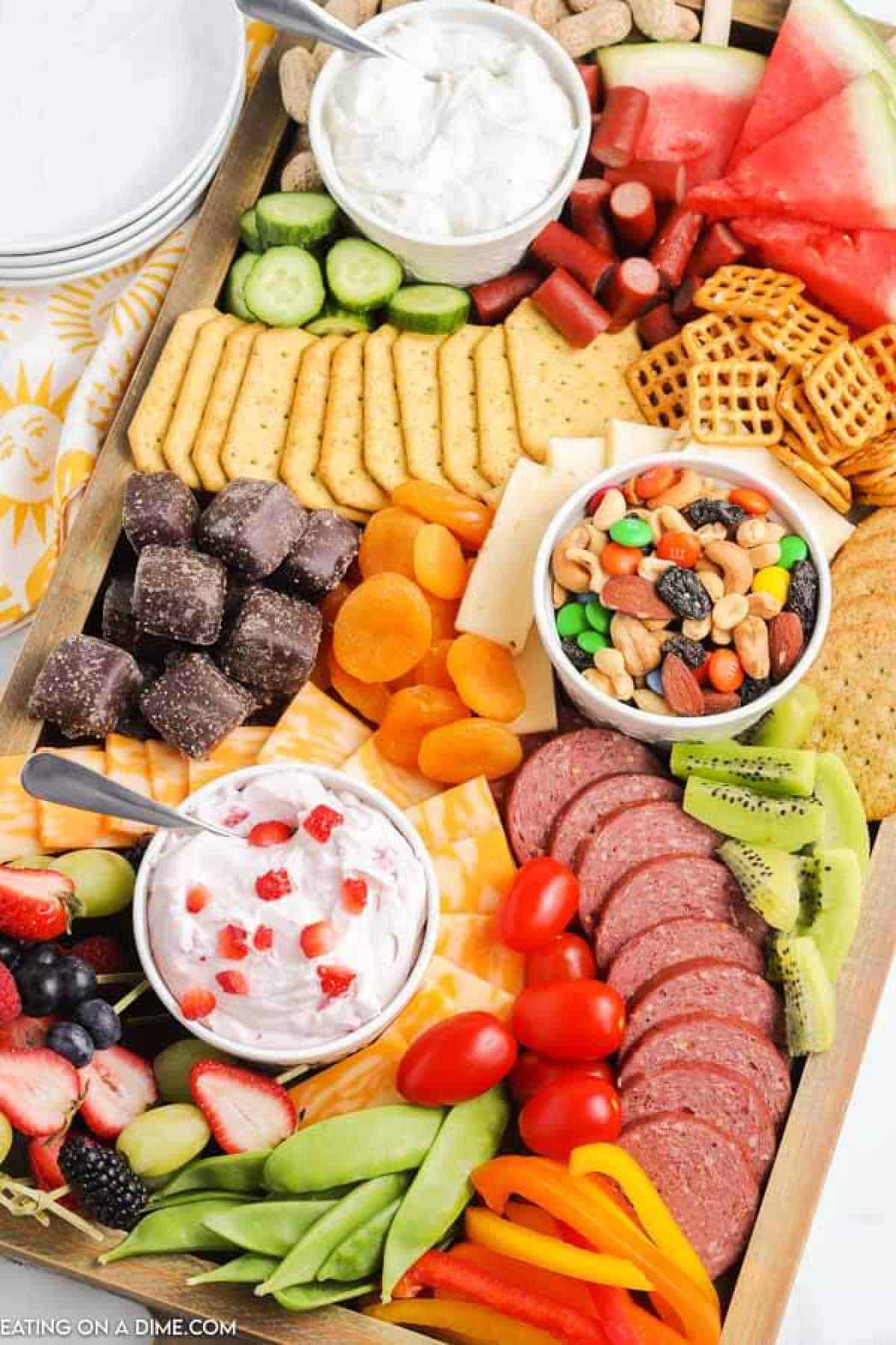 Summer charcuterie board with fruit, vegetables, chocolate, nuts and mote.