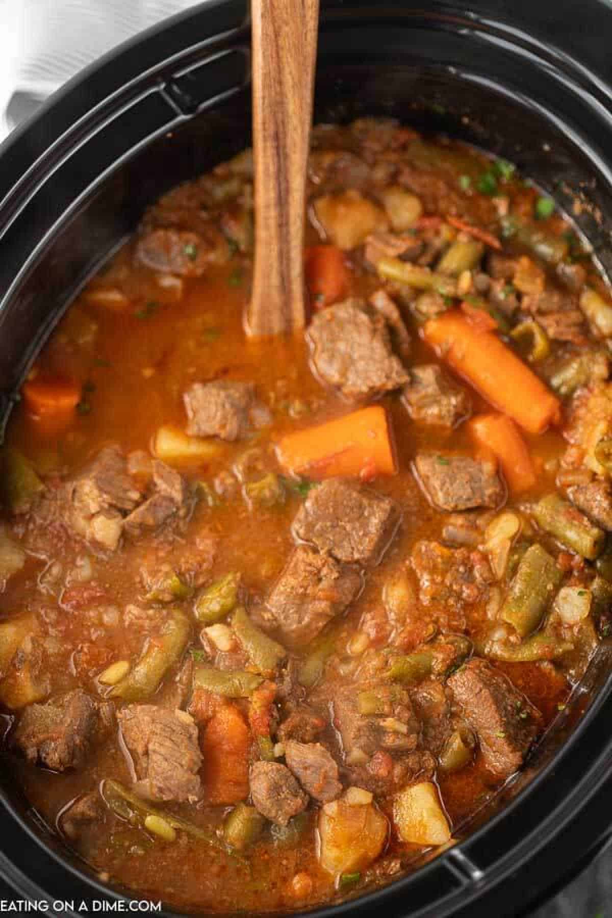 Beef Stew in the slow cooker with a wooden spoon