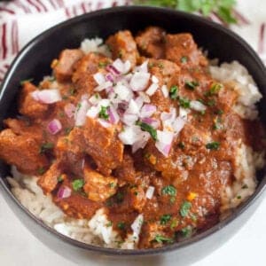 Beef Curry in a bowl topped with red onions.