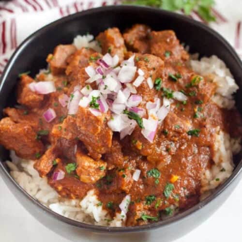 Beef Curry in a bowl topped with red onions.