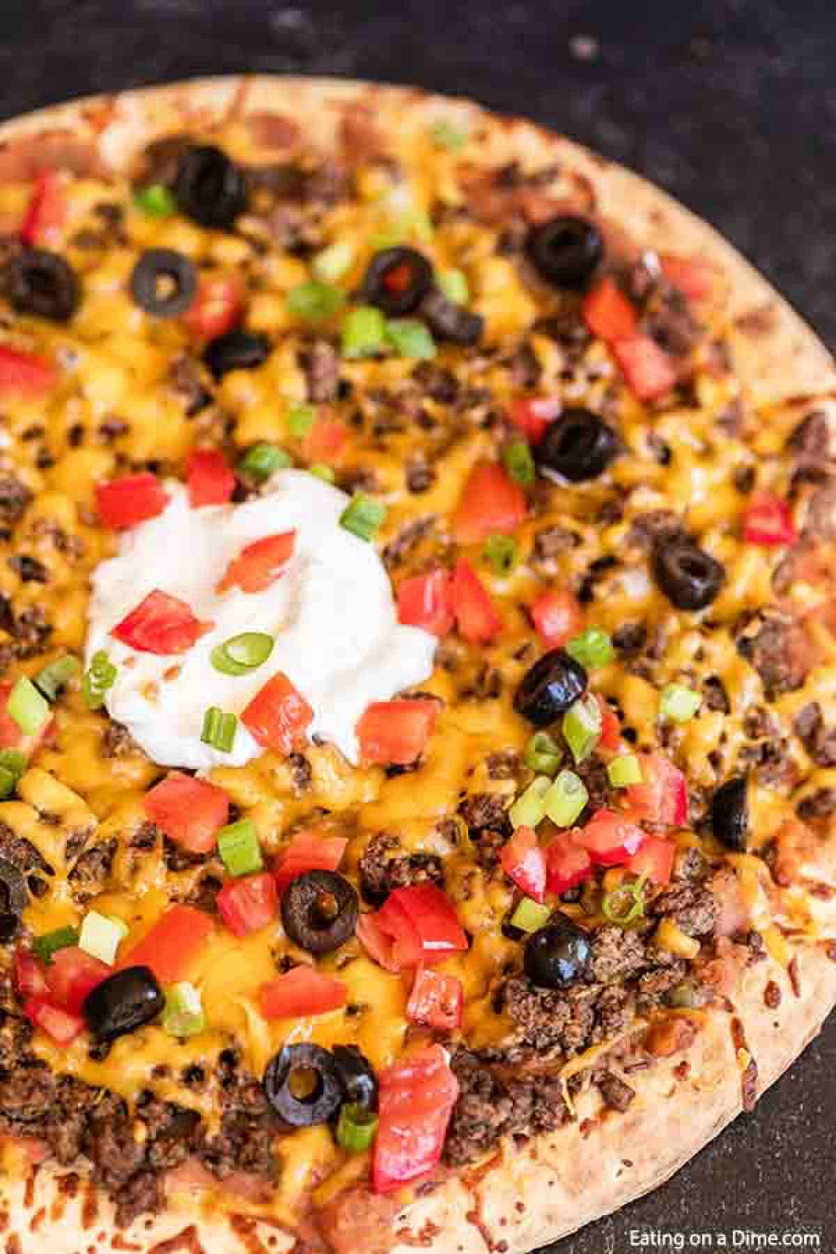 Our family loves this Taco pizza recipe with pizza crust and it is so easy to prepare. This easy homemade Mexican pizza with refried beans is loaded with so much flavor and tons of delicious toppings. #eatingonadime #tacopizzarecipe