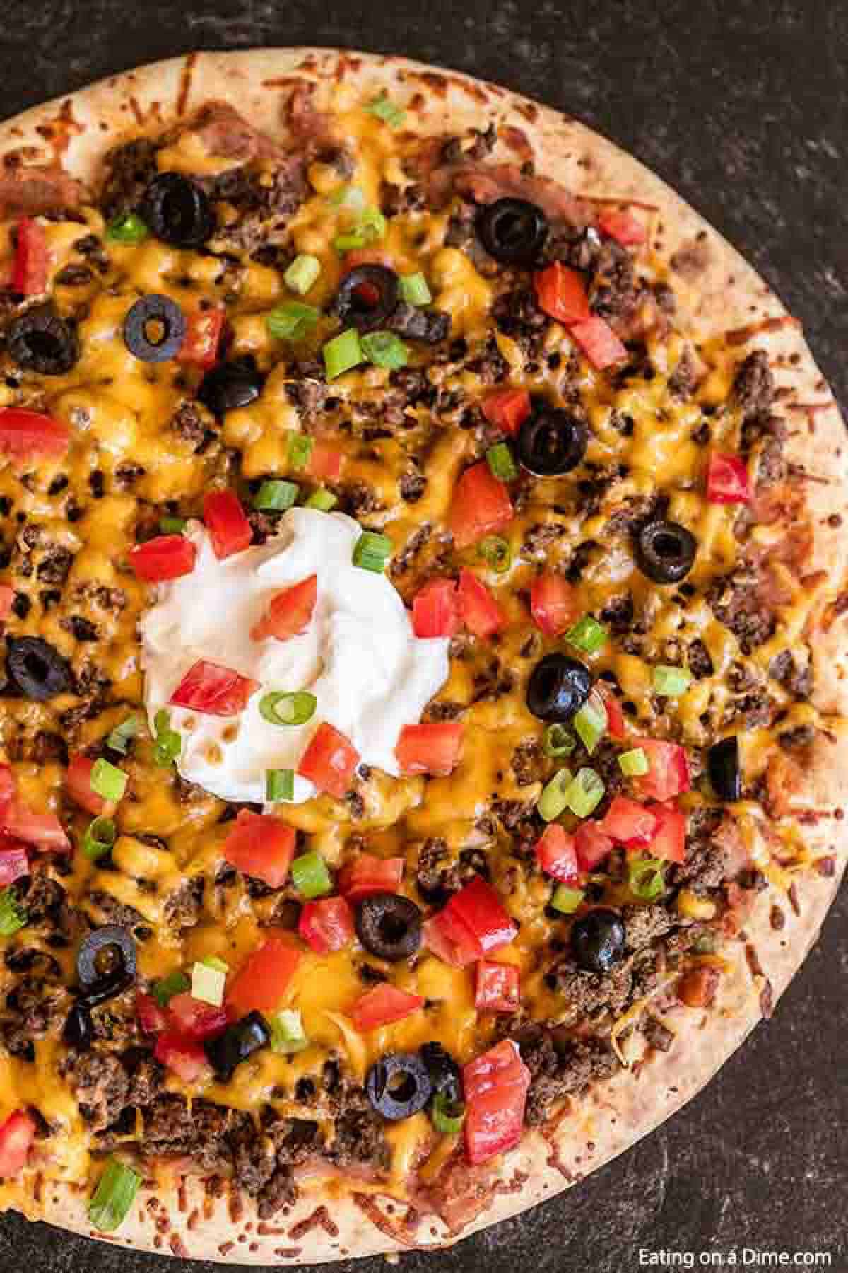 Our family loves this Taco pizza recipe with pizza crust and it is so easy to prepare. This easy homemade Mexican pizza with refried beans is loaded with so much flavor and tons of delicious toppings. #eatingonadime #tacopizzarecipe