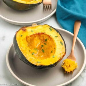 Roasted acorn squash sliced in half on a plate.