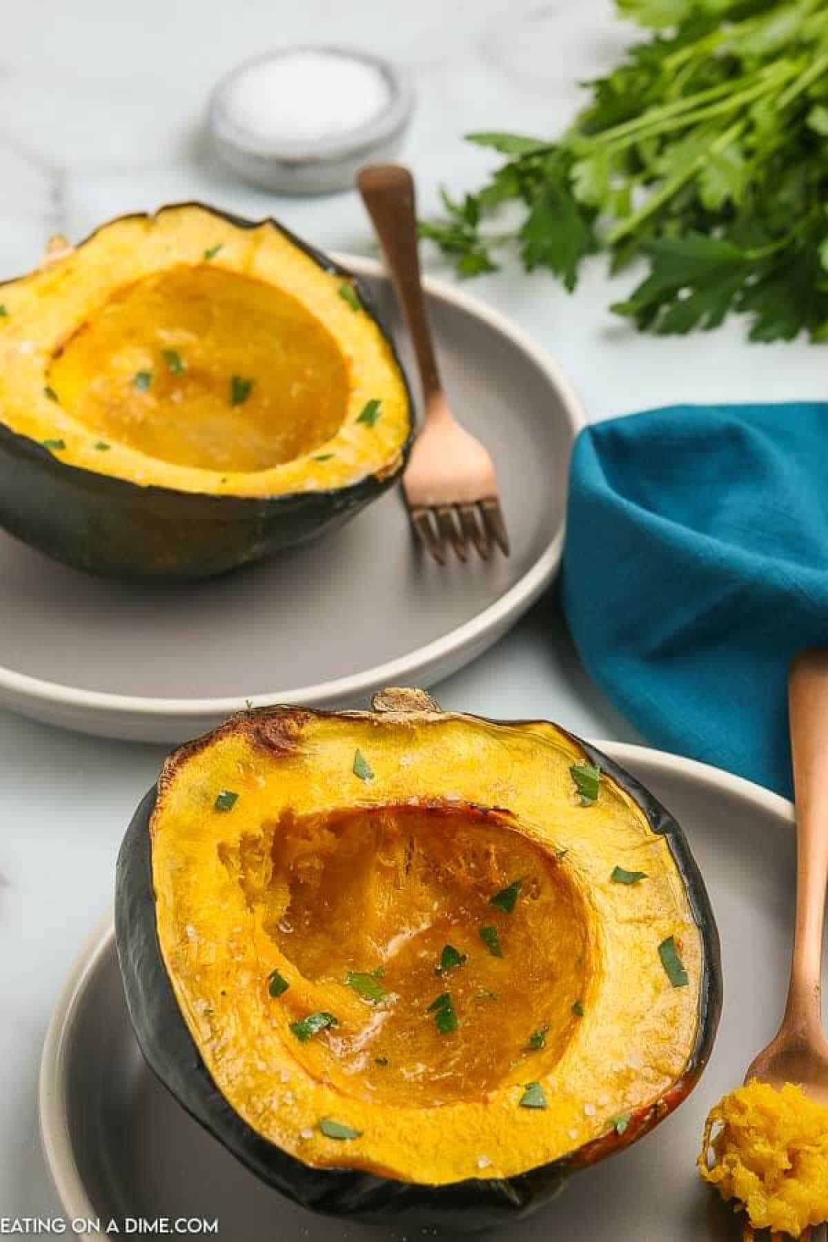Roasted acorn squash recipe is super easy and really healthy. You only need 5 ingredients for this flavor packed side dish. Learn how to roast acorn squash in oven with brown sugar and maple syrup. Find out how to roast acorn squash for a savory or sweet side dish option. #eatingonadime #roastedacornsquash #recipes #recipeshealthy #Recipesbrownsugar #roastedacornsquashoven #Howlongto #oven #howto Roasted Acorn Squash half on a plate