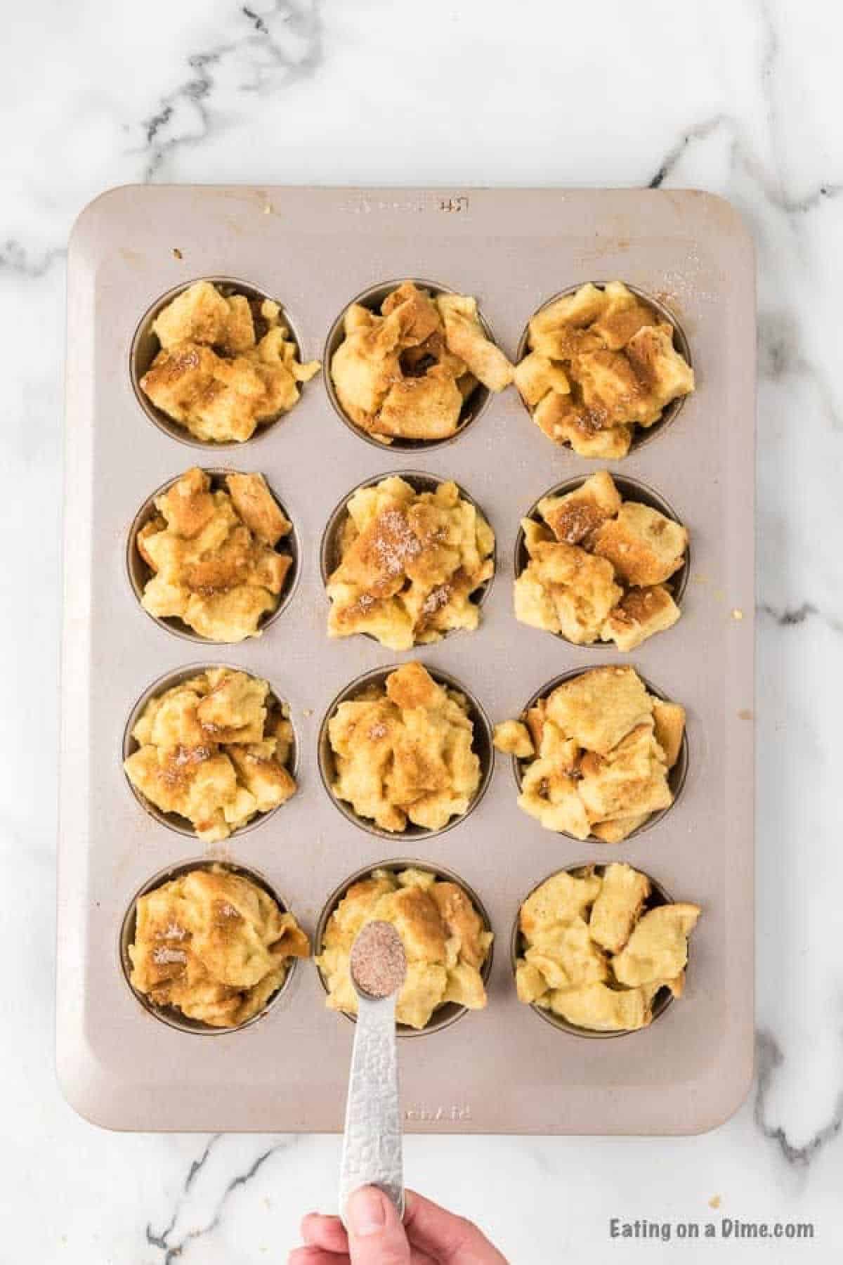 Bread pieces in a muffin pan topped with cinnamon and sugar mixture
