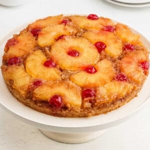 Pineapple upside down cake on a cake stand.