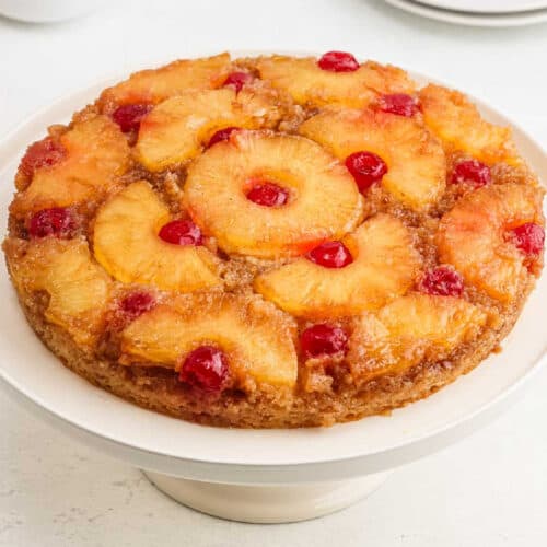 Pineapple upside down cake on a cake stand.