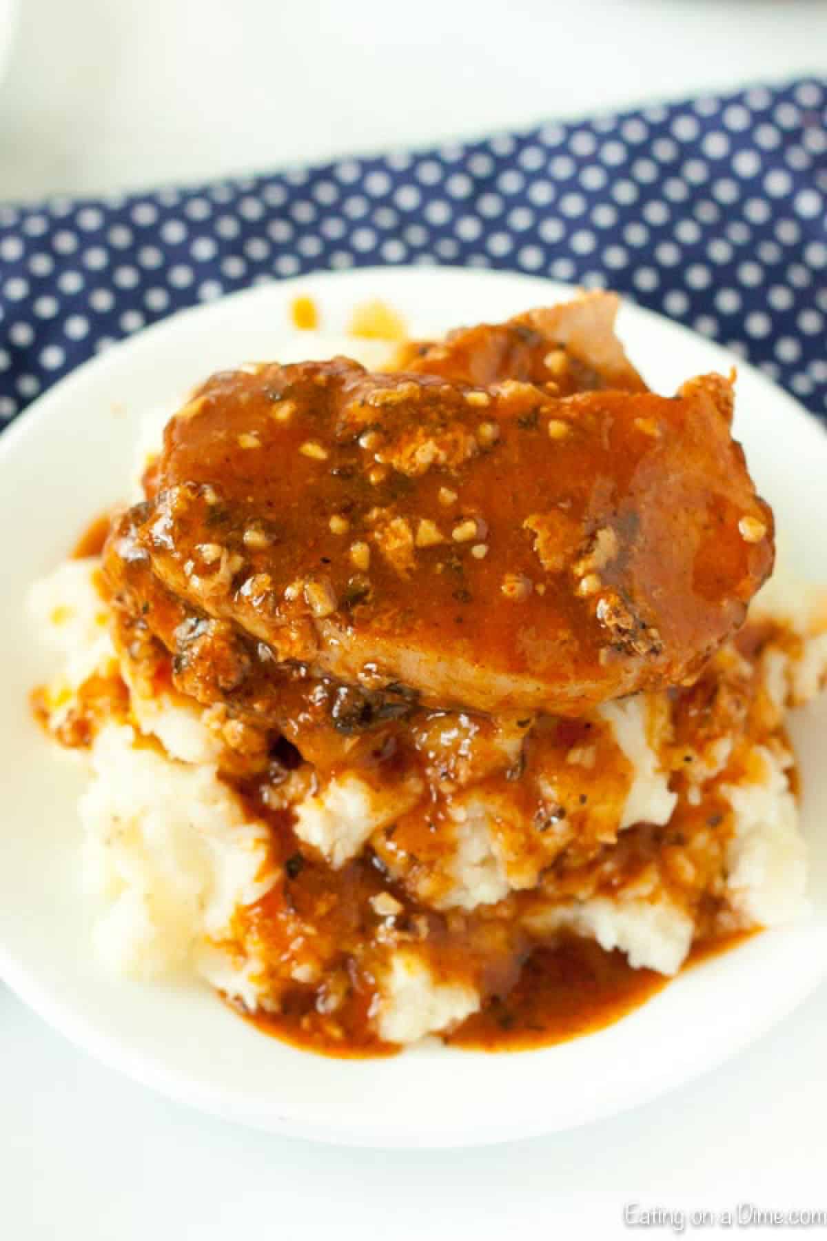 Pork chops covered with gravy over mashed potatoes on a plate