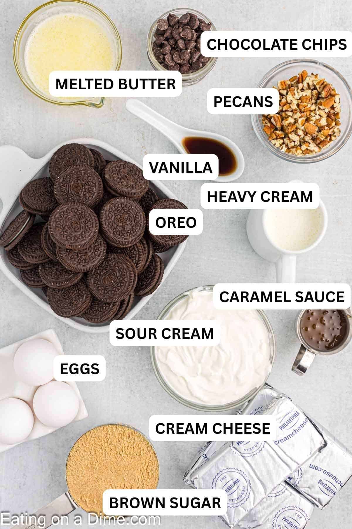The ingredients required to make the recipe prepared on the countertop. Includes Oreo cookies, melted butter, cream cheese, brown sugar and more.