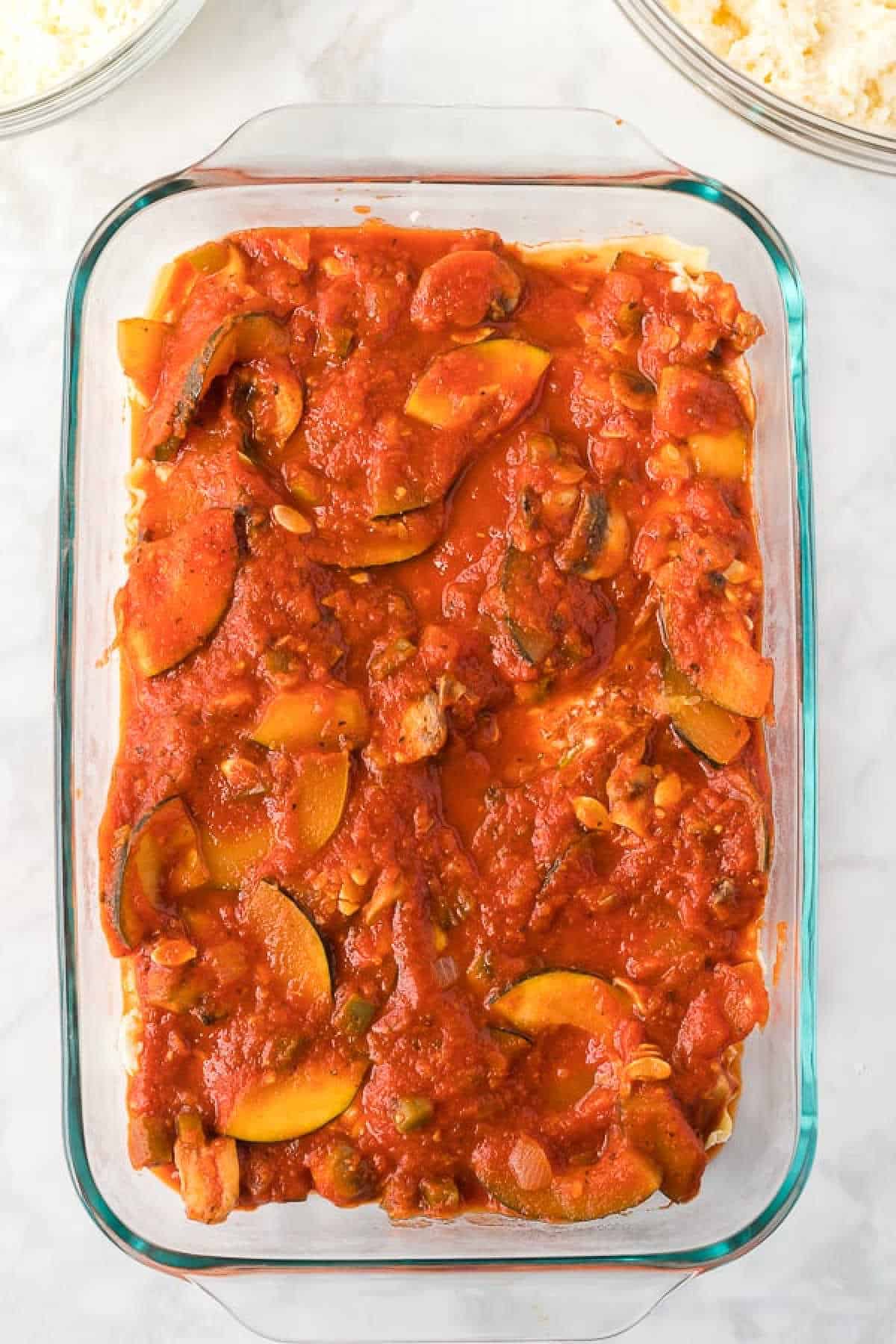 Topping the noodles with the vegetable sauce mixture in a baking dish