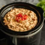 Cheeseburger dip in a small crock pot topped with diced tomatoes.