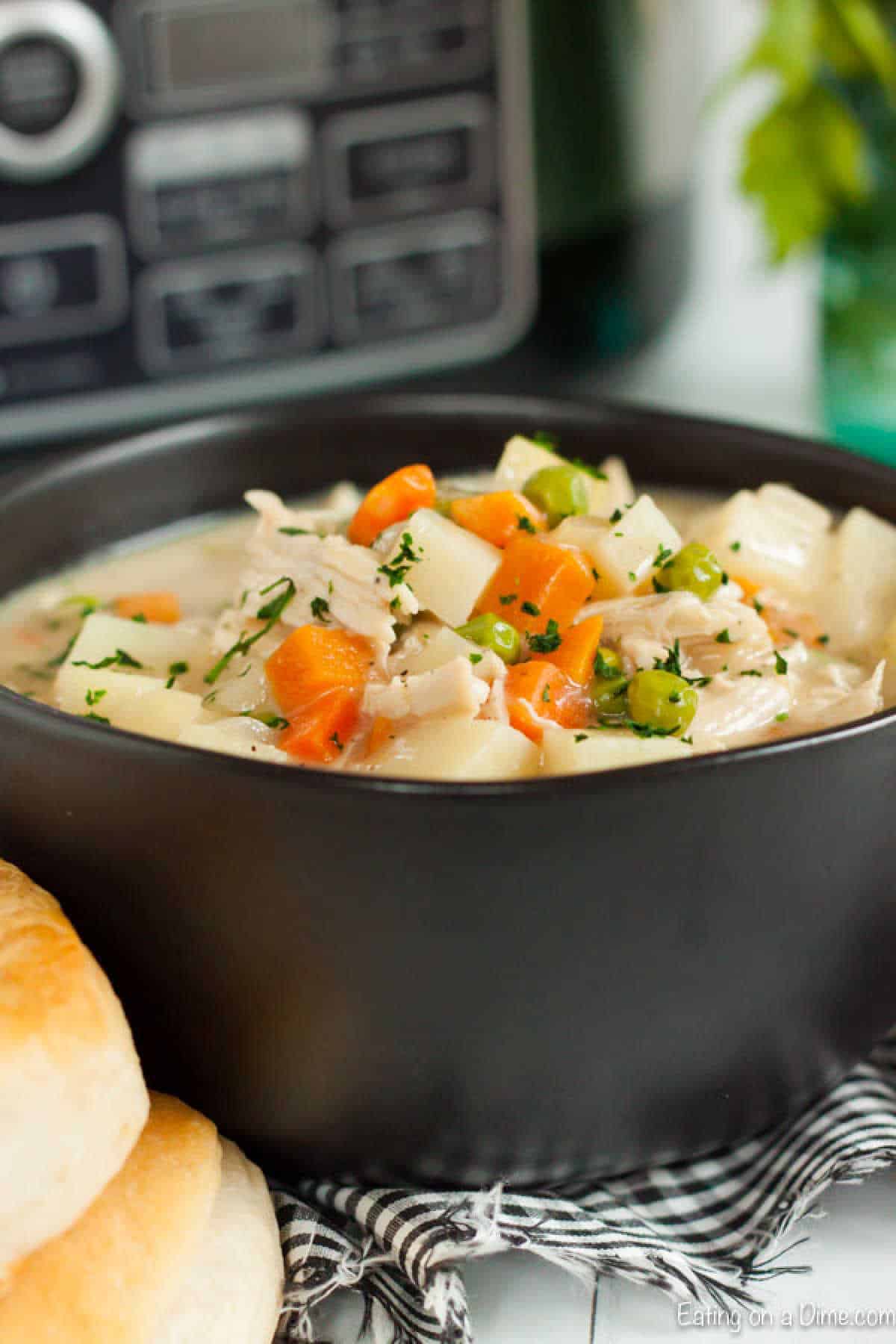Chicken pot pie soup in a bowl topped with diced potatoes, carrots and peas