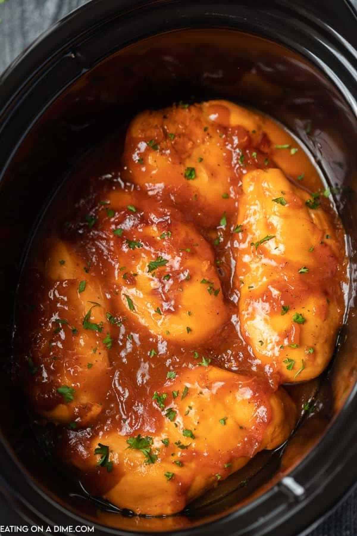 Crock pot catalina chicken is sweet and tangy and the combination turns chicken into something special. The crockpot makes dinner a breeze. Close up image of catalina chicken in the crock pot