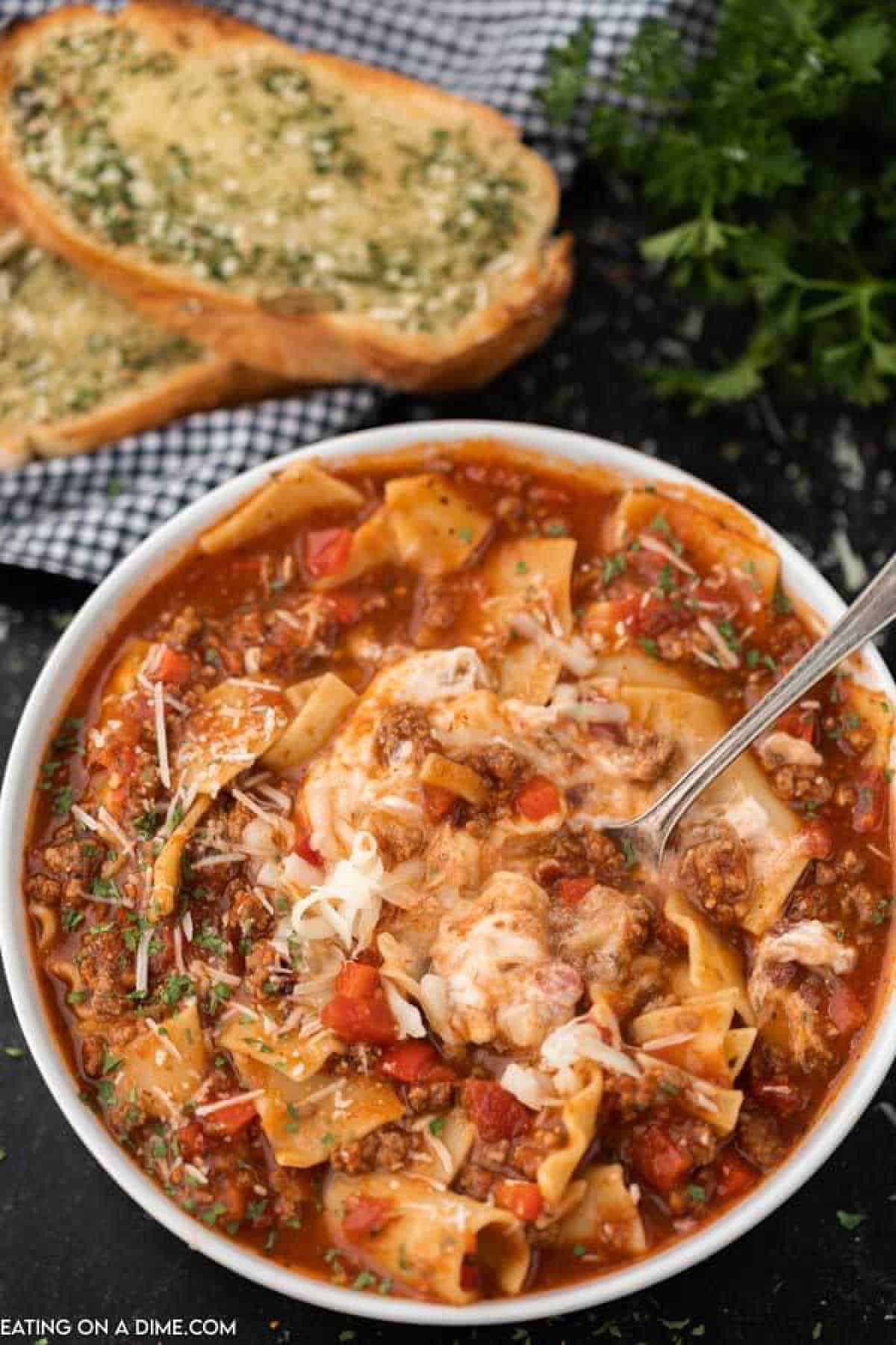 A bowl of lasagna soup with a spoon in it scooping a bite out of the soup!