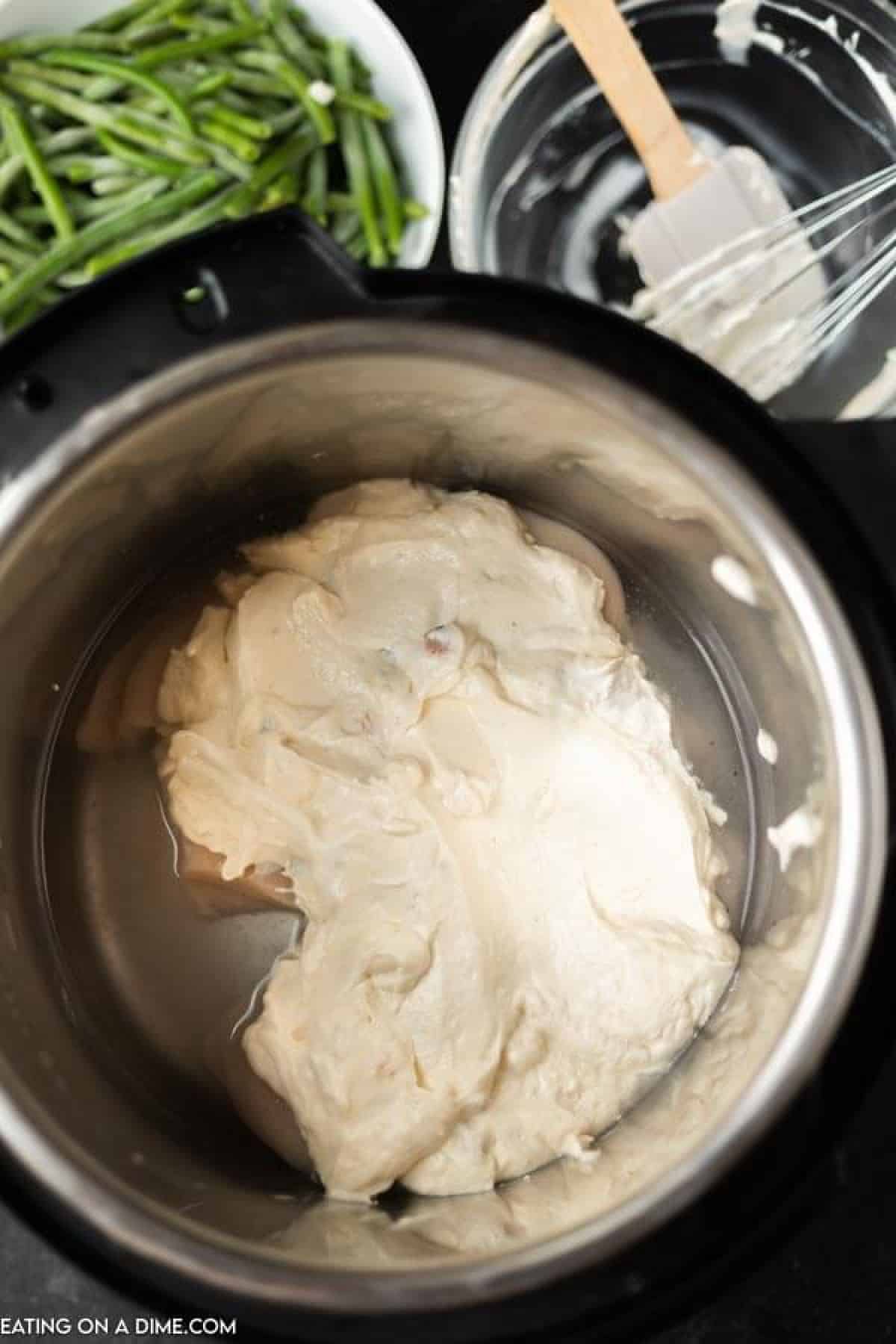Spreading the sour cream mixture over the chicken breast in the instant pot