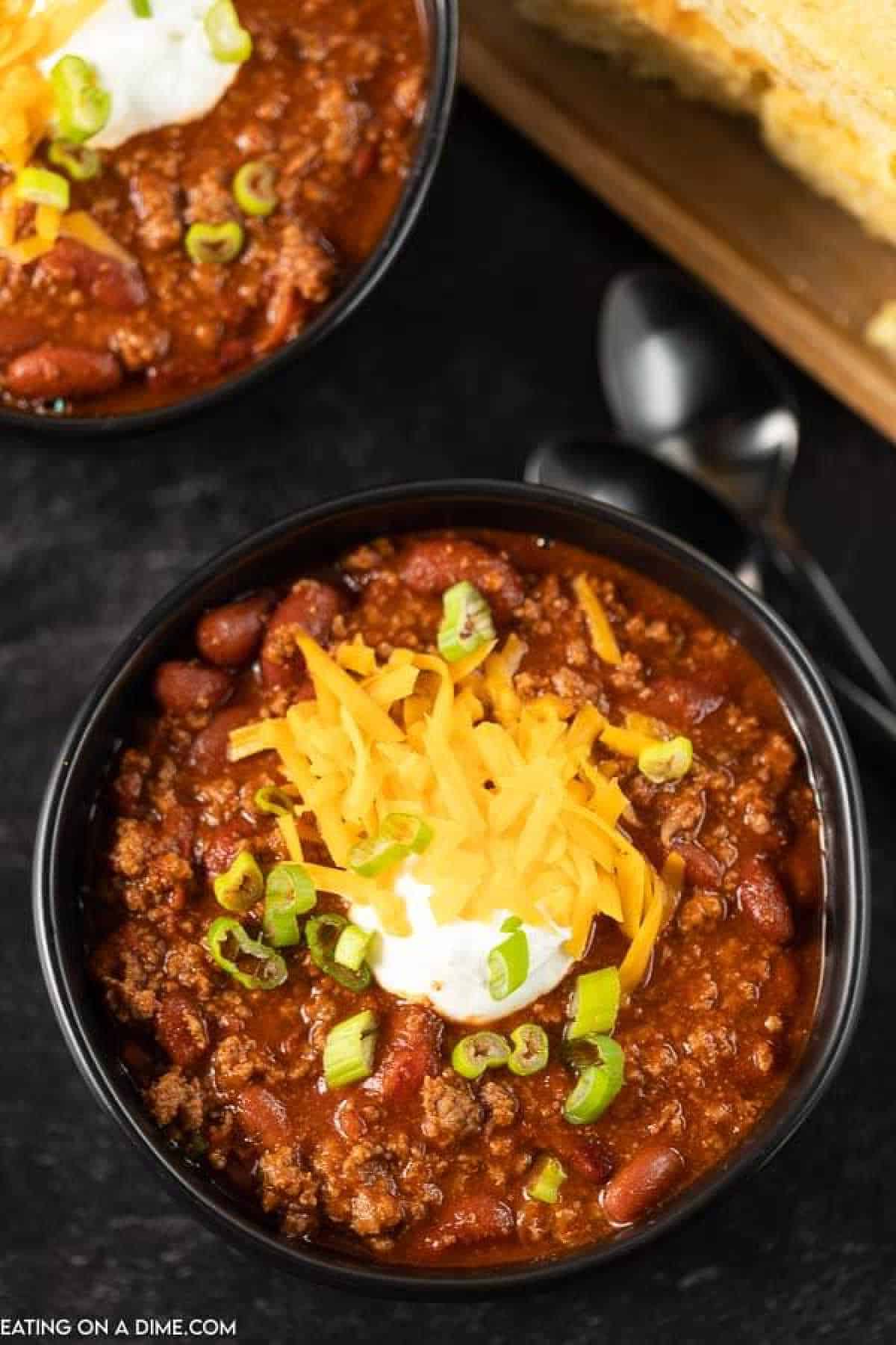 Chili in a bowl topped with shredded cheese, sour cream and green onions
