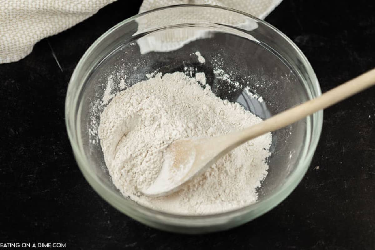 A bowl of flour with a wooden spoon