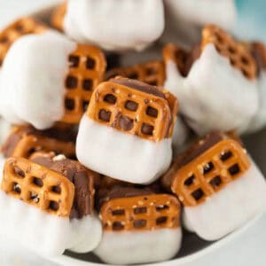 A bowl filled with Snicker Chocolate Pretzels—treats made of marshmallows and chocolate sandwiched between pretzels, each half-dipped in white chocolate.